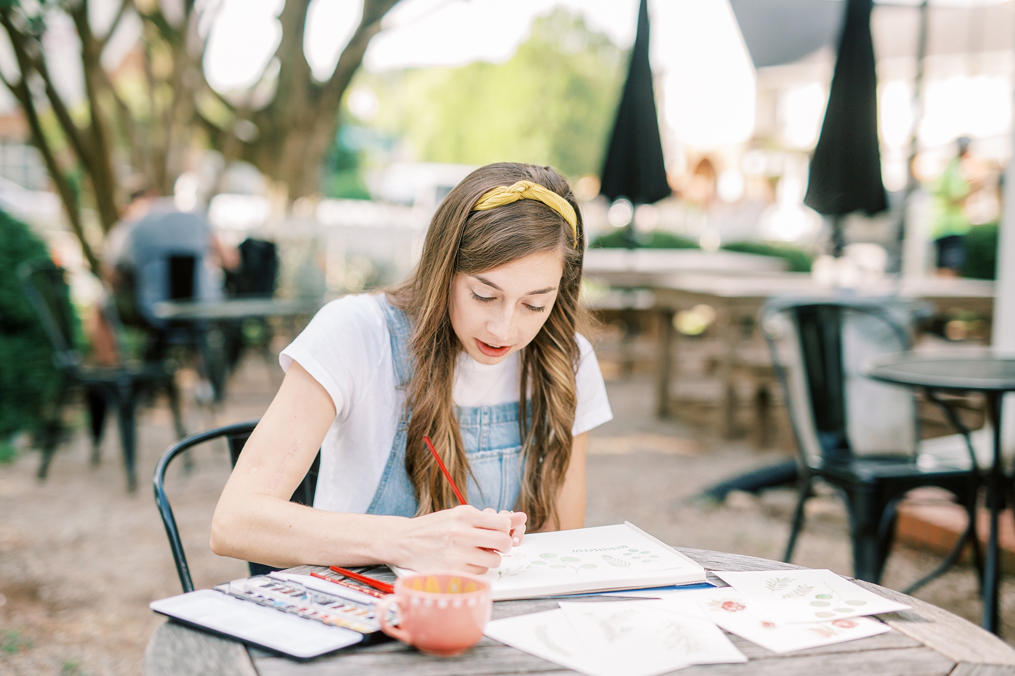 watercolor wedding invitations designer works during branding photos in Charlotte NC cafe
