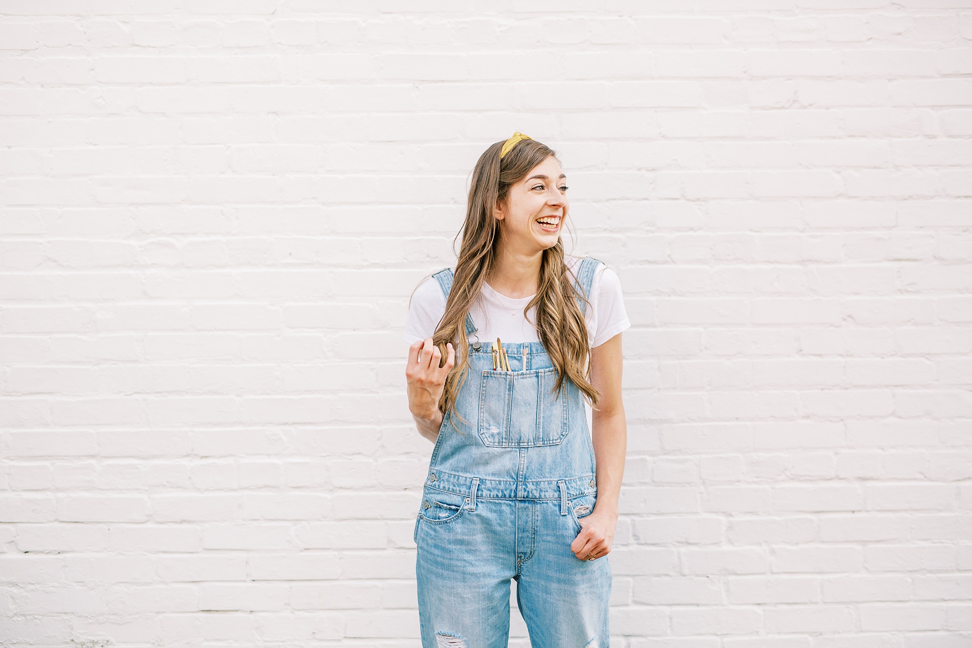 watercolor wedding invitations designer poses in front of white wall in Charlotte NC
