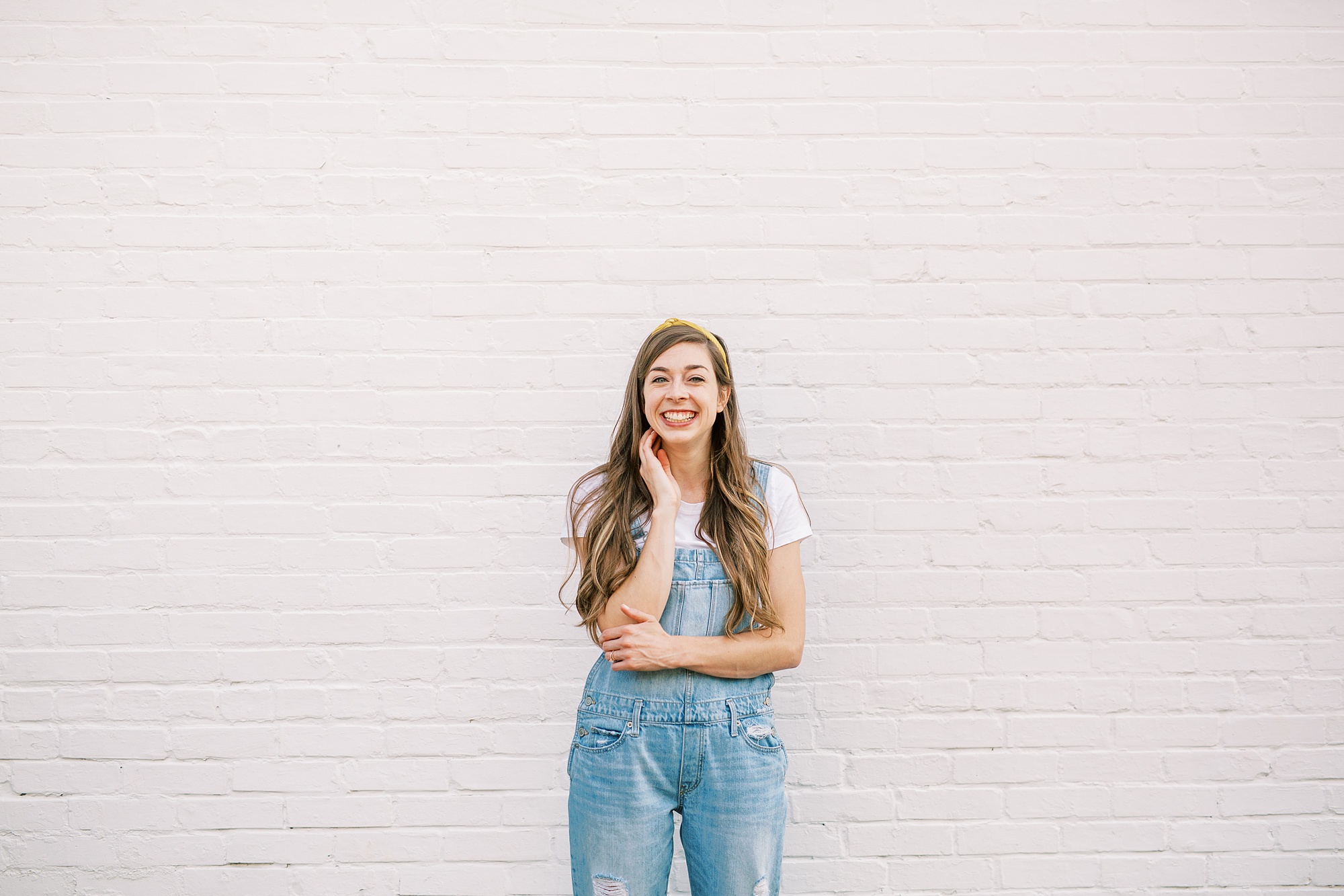artist in overalls poses by white walls in Charlotte NC