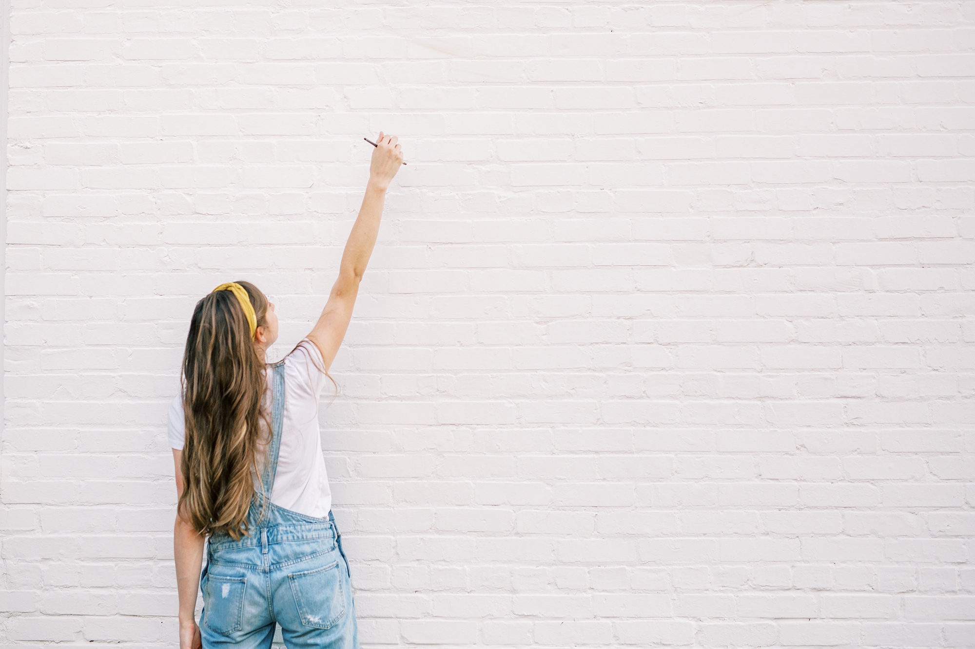 artist pretends to write on white wall during branding photos