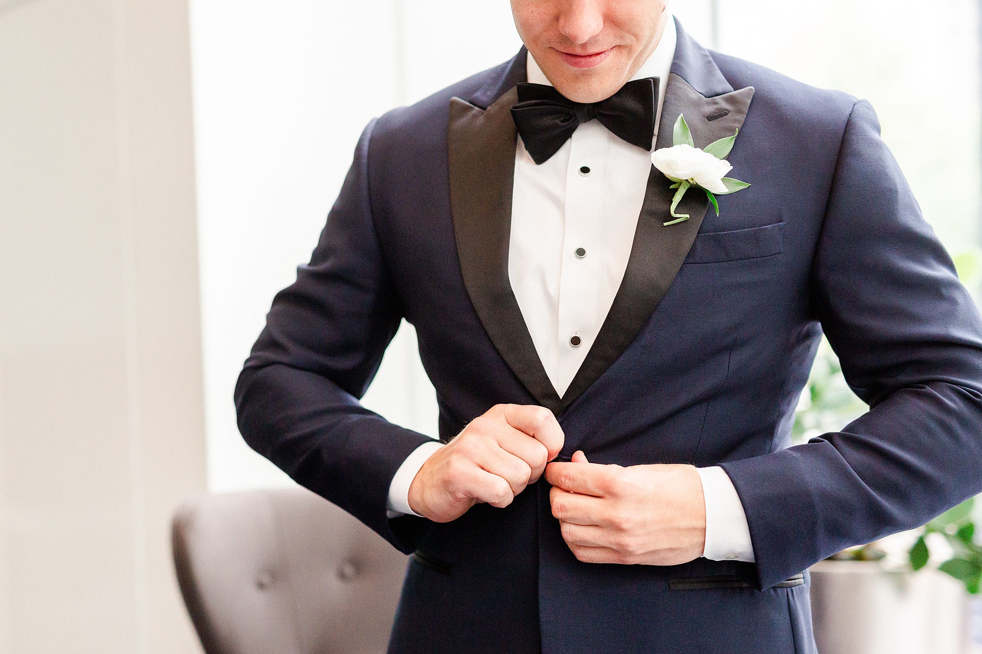 groom buttons up tux during portraits at Kimpton hotel