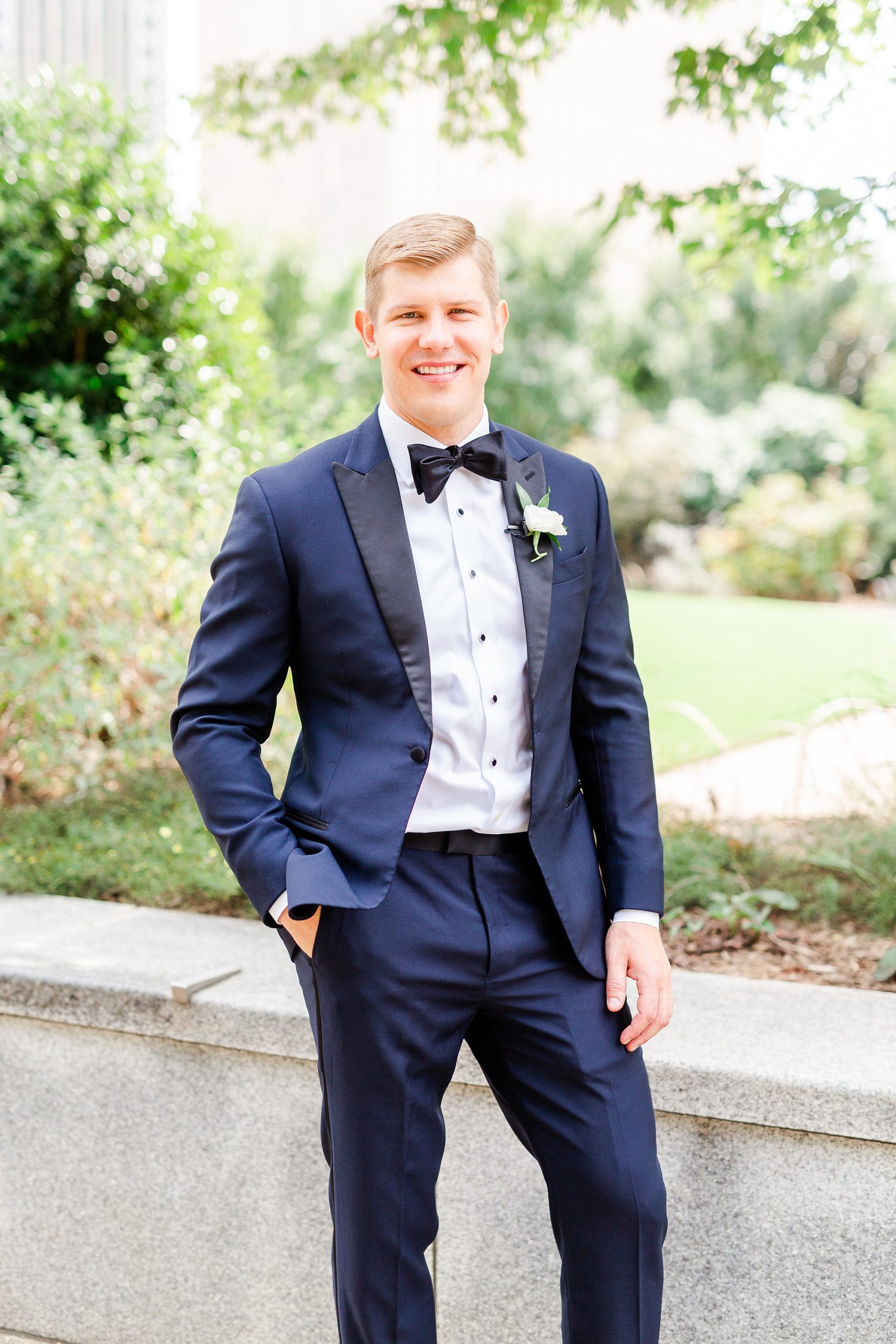 groom in navy tux poses in Romare Bearden Park