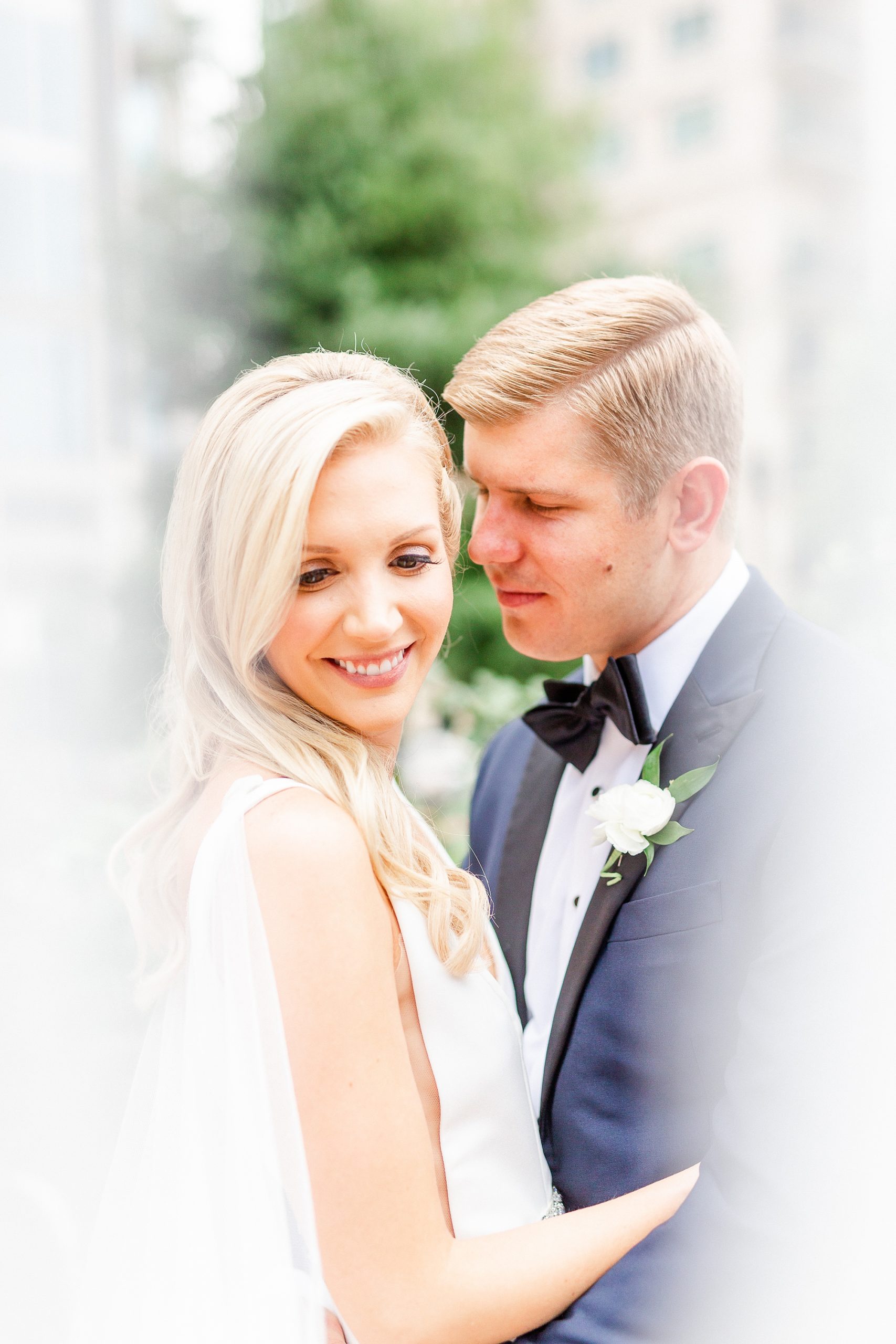 groom whispers to bride while veil is draped around them