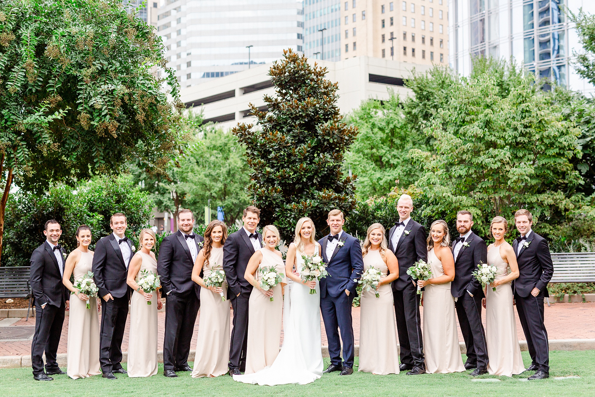 bridal party poses in front of Charlotte skyline