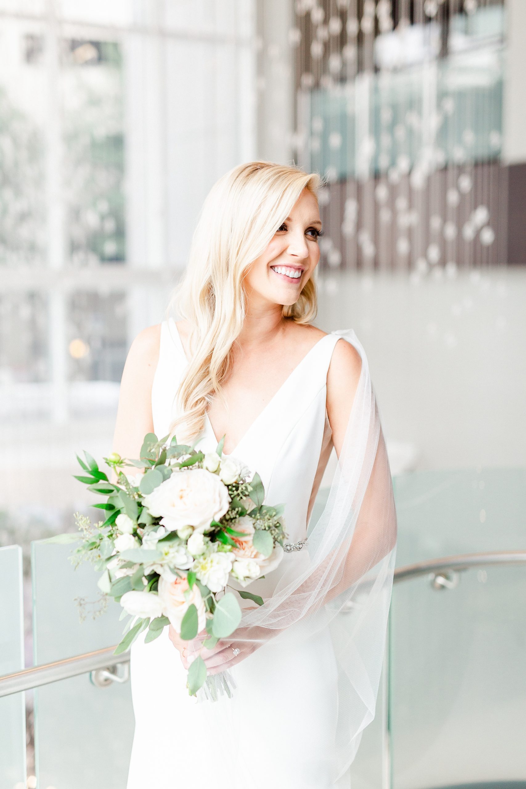 bride holds bouquet of white flowers with waterfall behind her