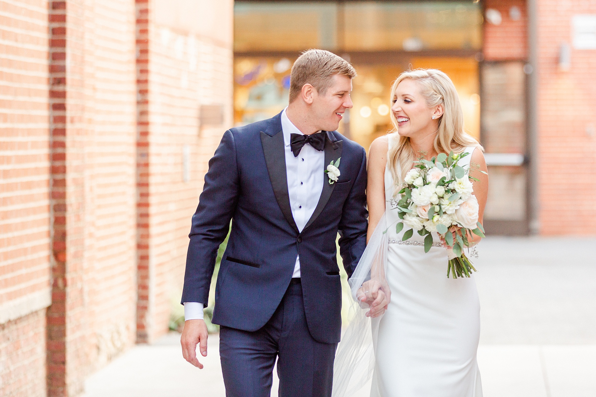 newlyweds hold hands and walk down side street by Byron's South End
