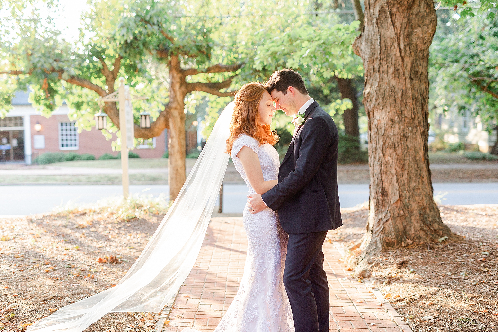 newlyweds stand with heads touching during classic Southern wedding portraits