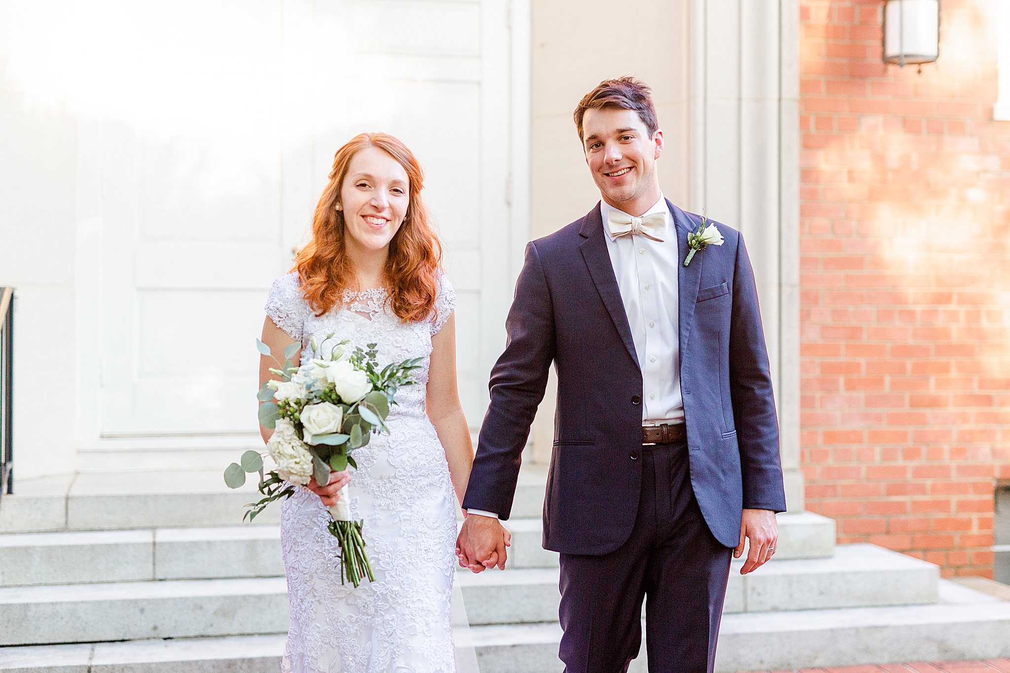 newlyweds hold hands and walk away from church