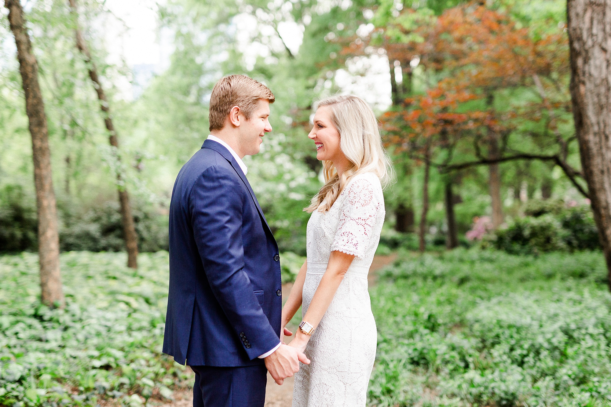 bride and groom hold hands during walk in the park