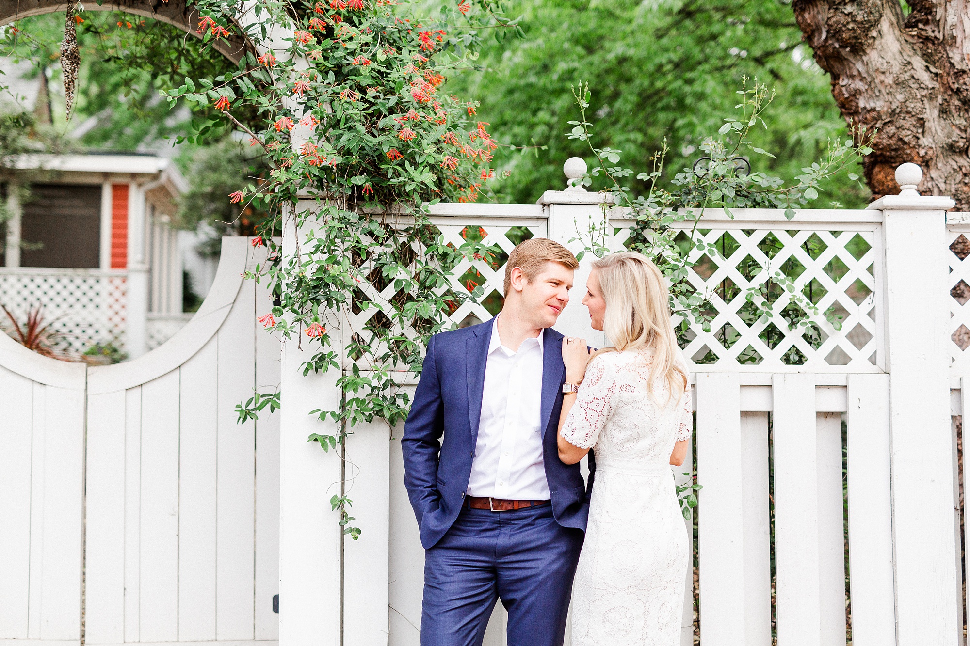 bride and groom pose by white fence in Charlotte NC