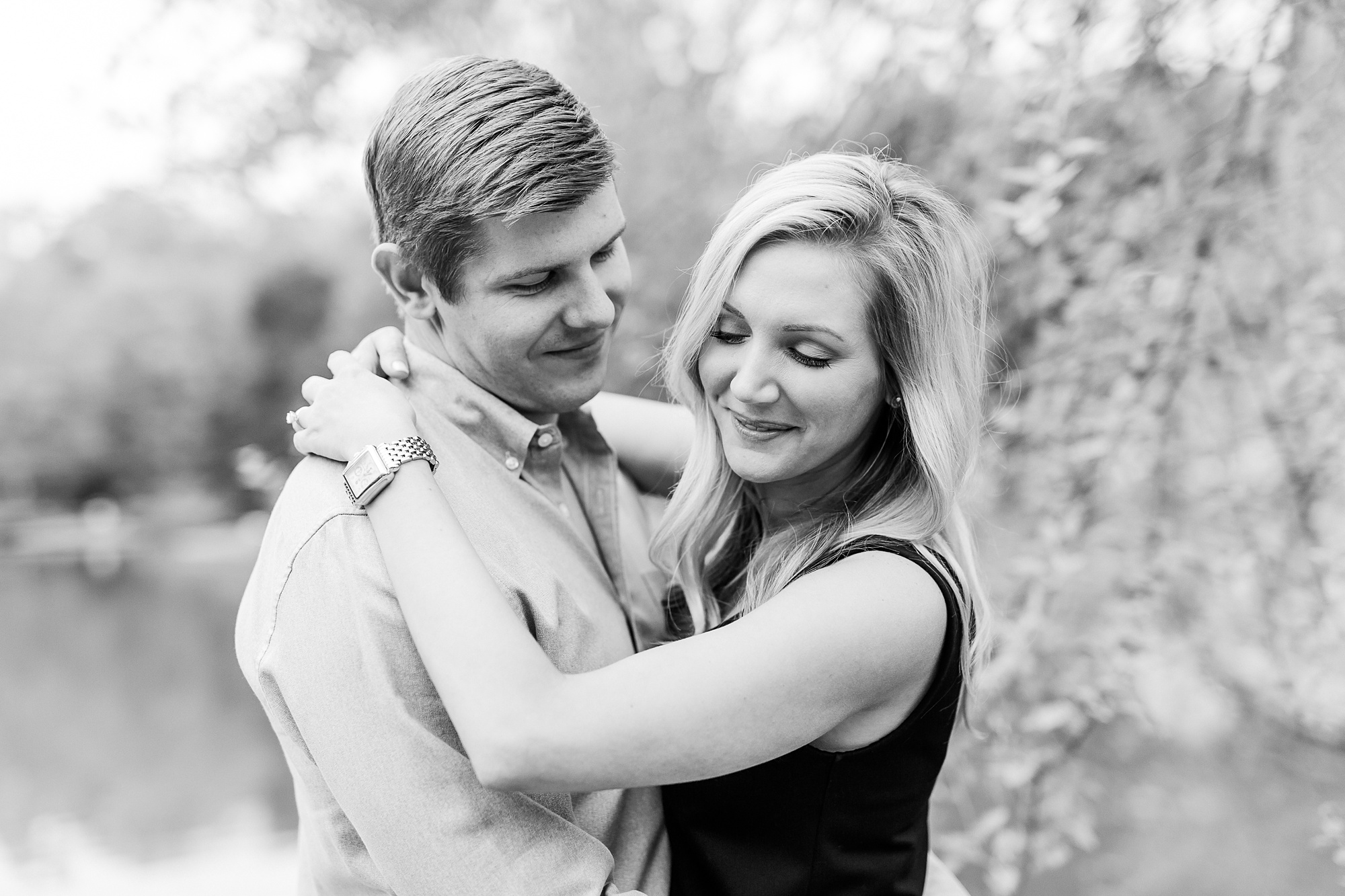 engaged couple hugs by pond at Freedom Park