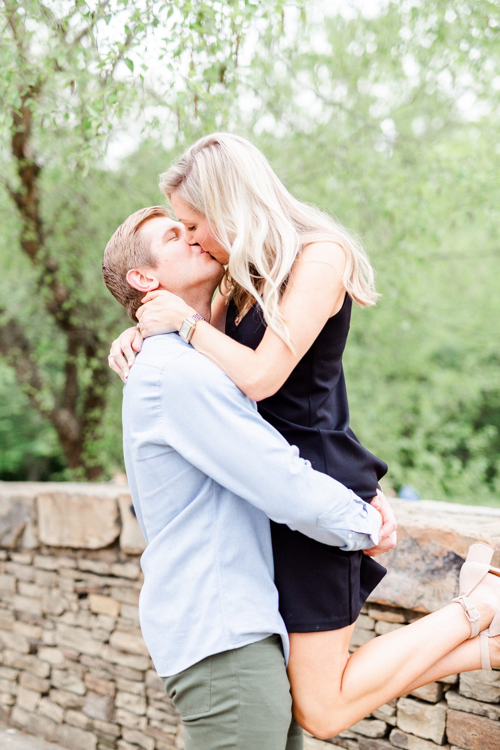groom lifts bride up on bridge during Freedom Park engagement photos