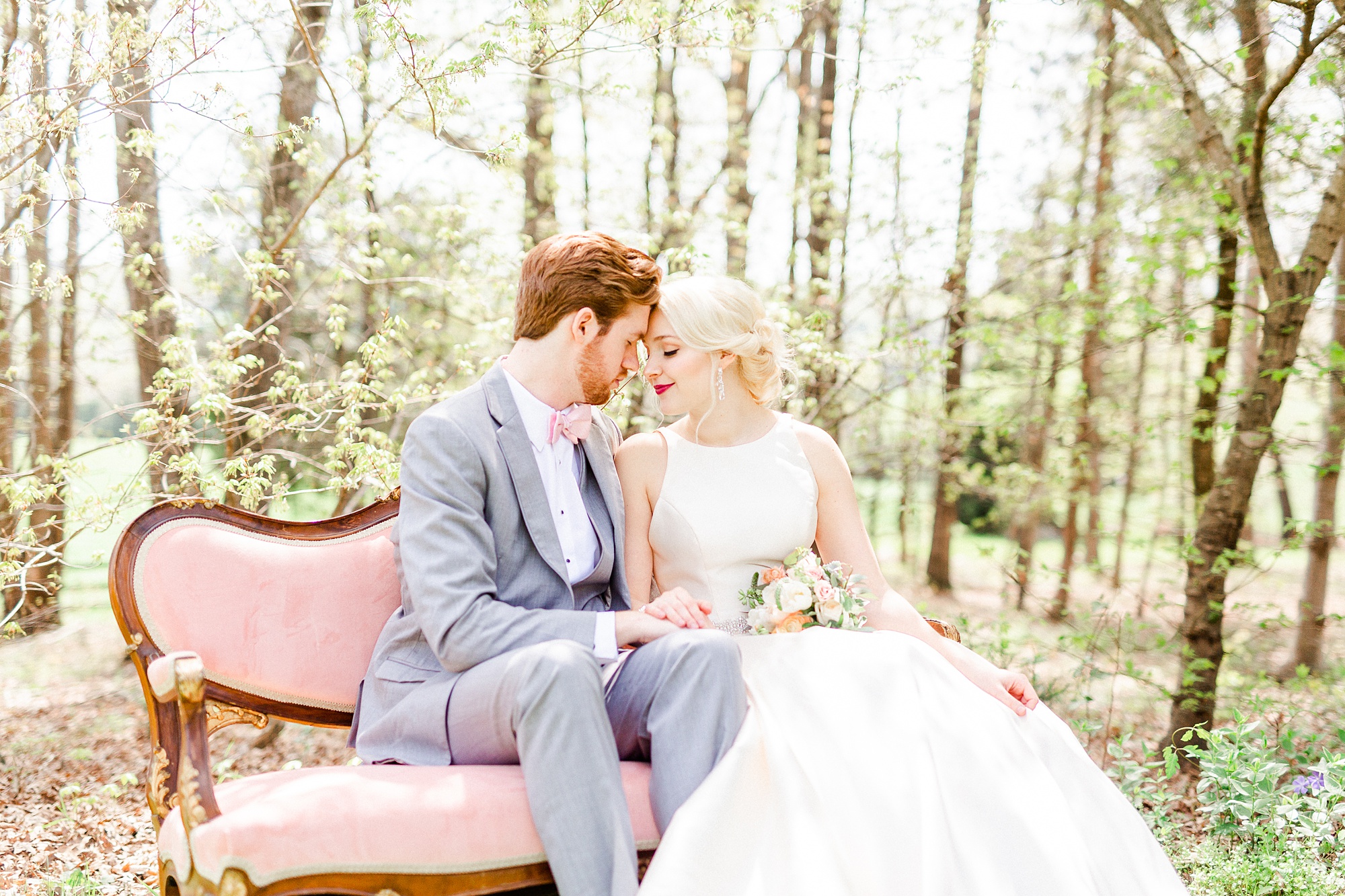 bride and groom cuddle on pink couch during wedding photos at Carolina Country Weddings