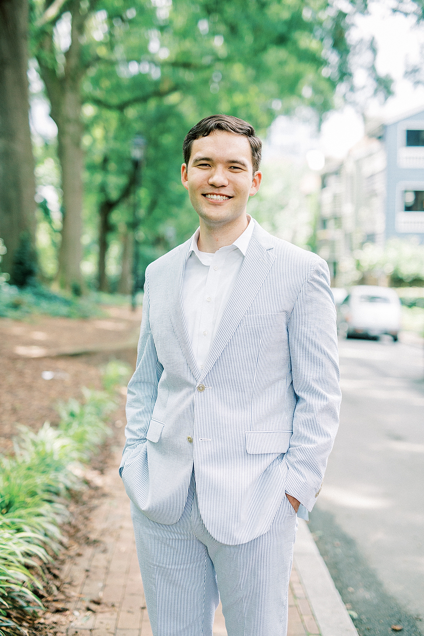 groom in blue suits poses in Fourth Ward Park