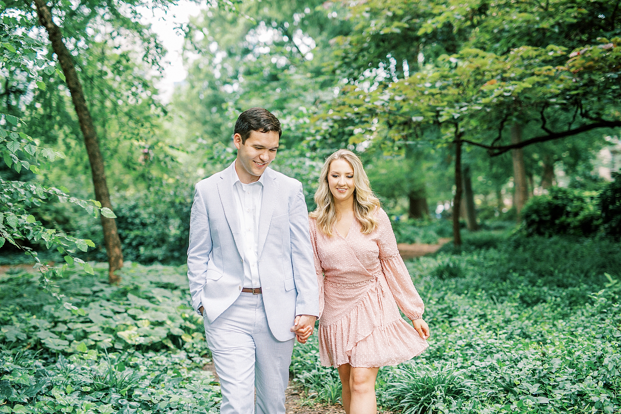 engaged couple holds hands walking through Fourth Ward Park