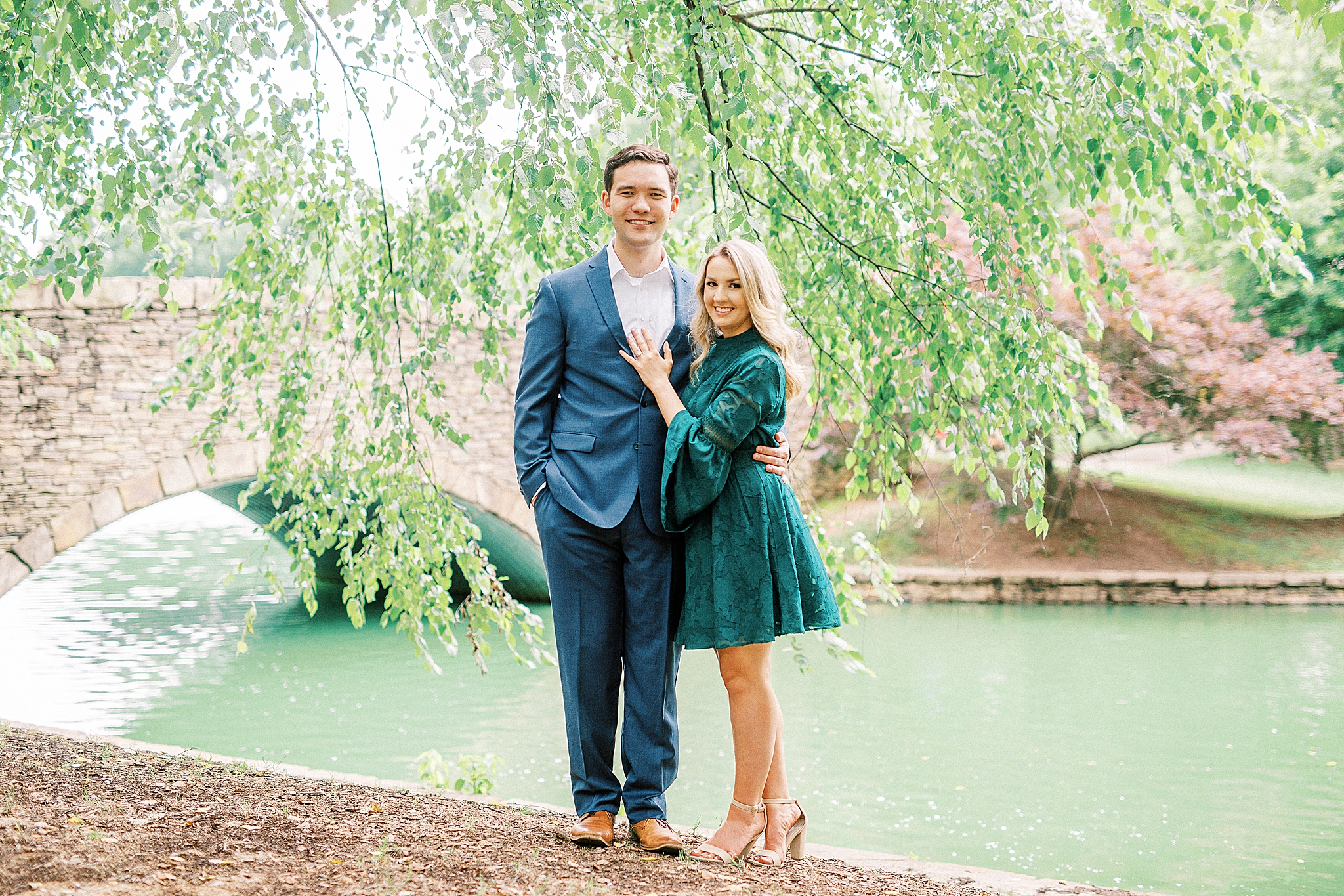 engaged couple poses by pond in Freedom Park