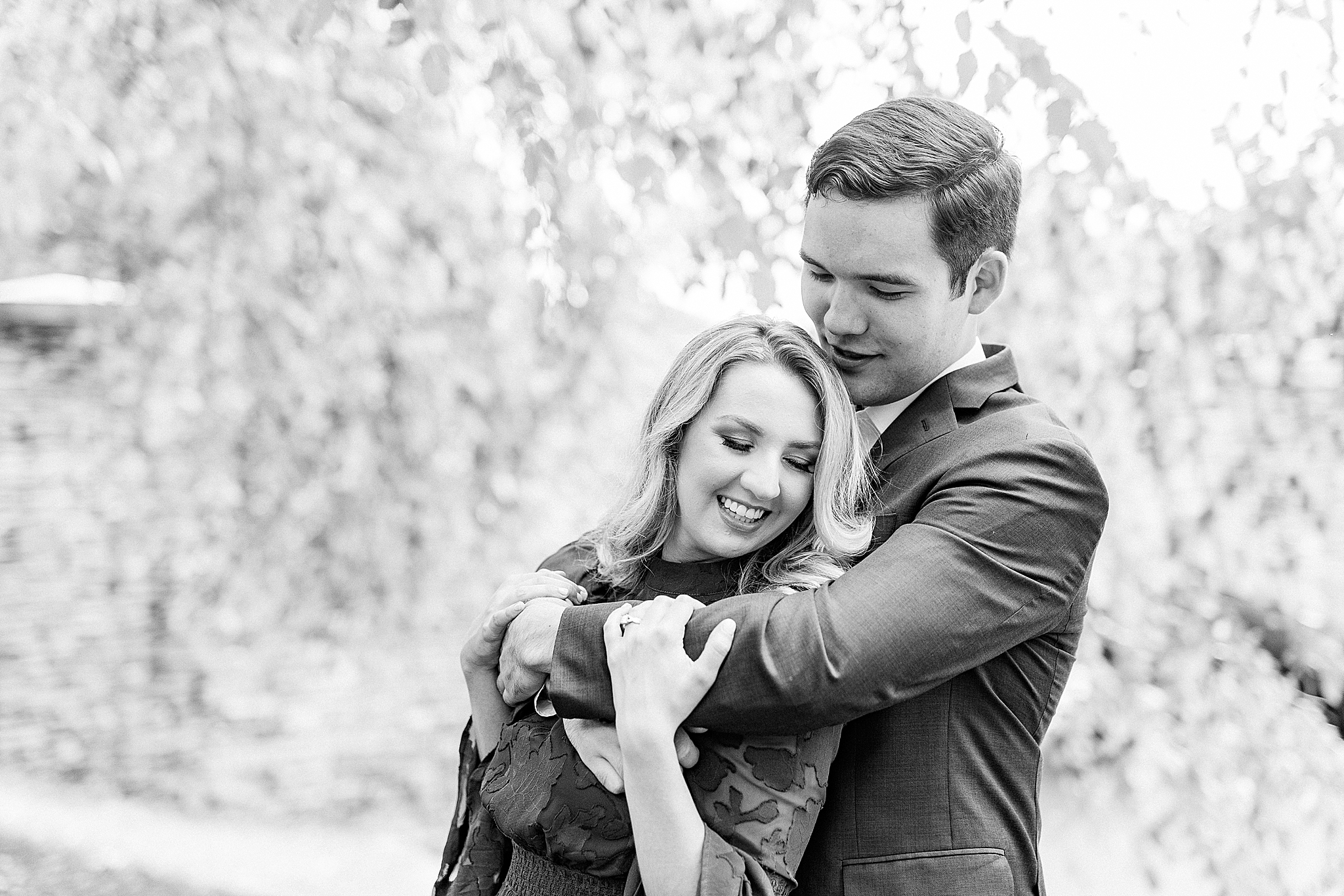 bride holds groom's arm around chest in uptown Charlotte
