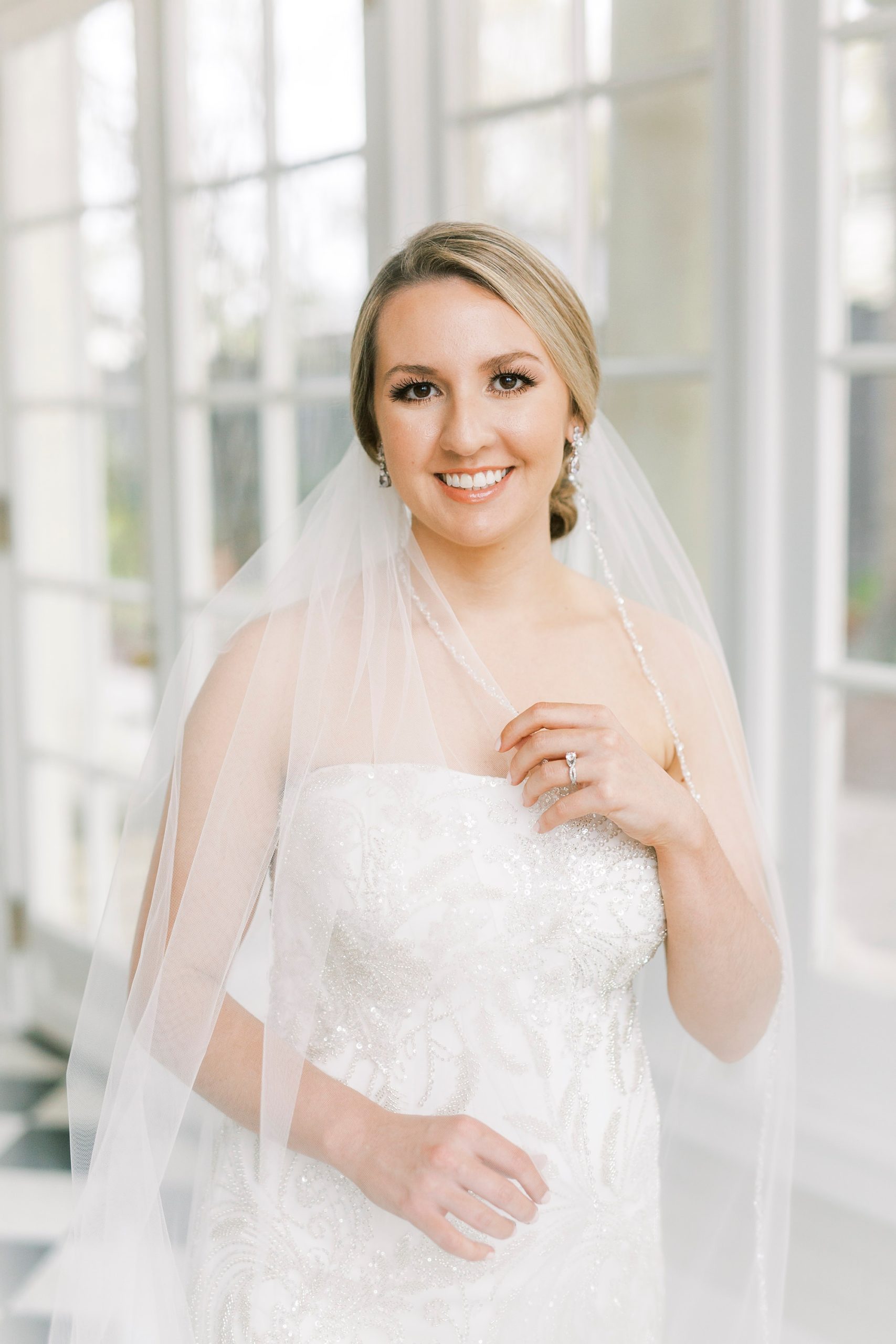 bride smiles holding cathedral veil around shoulders