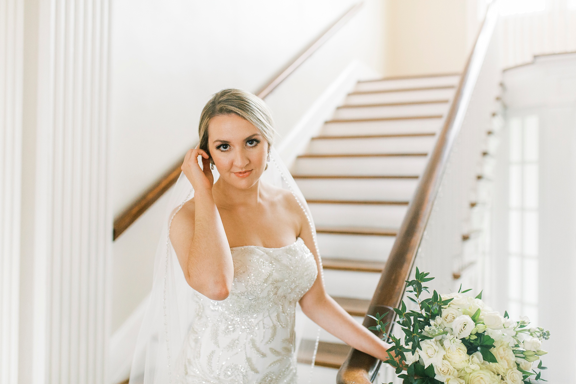 bride pushes hair behind ear during bridal portraits