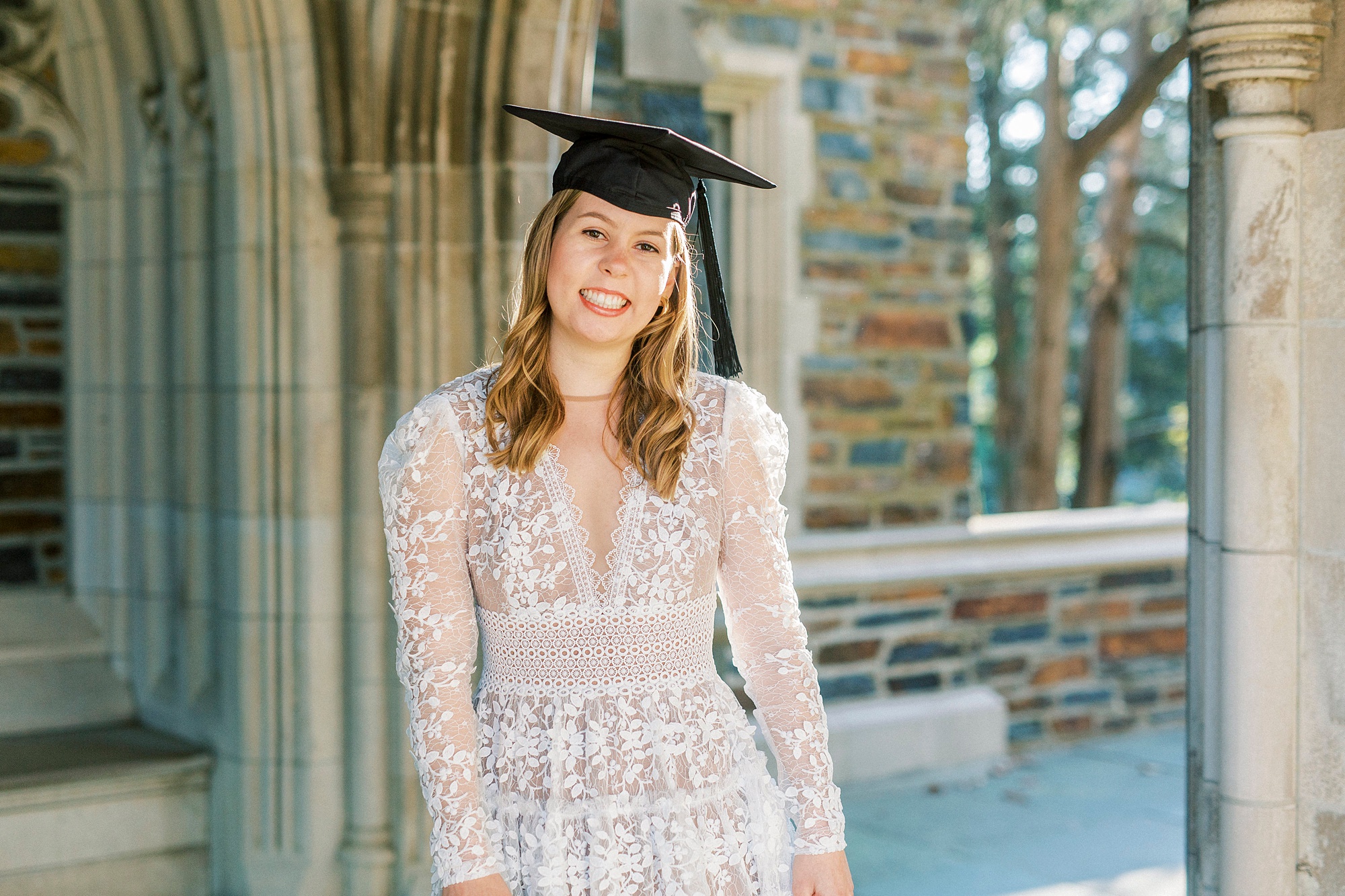 senior in graduation mortarboard smiles at Duke Chapel