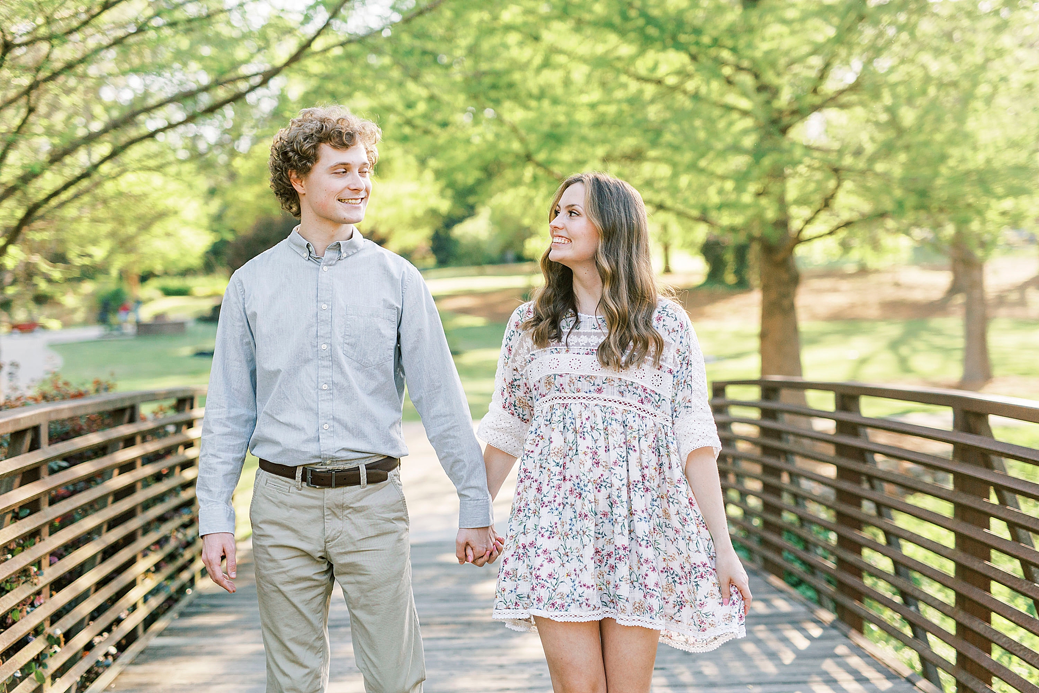 engaged couple walks on bridge in Glencairn Gardens