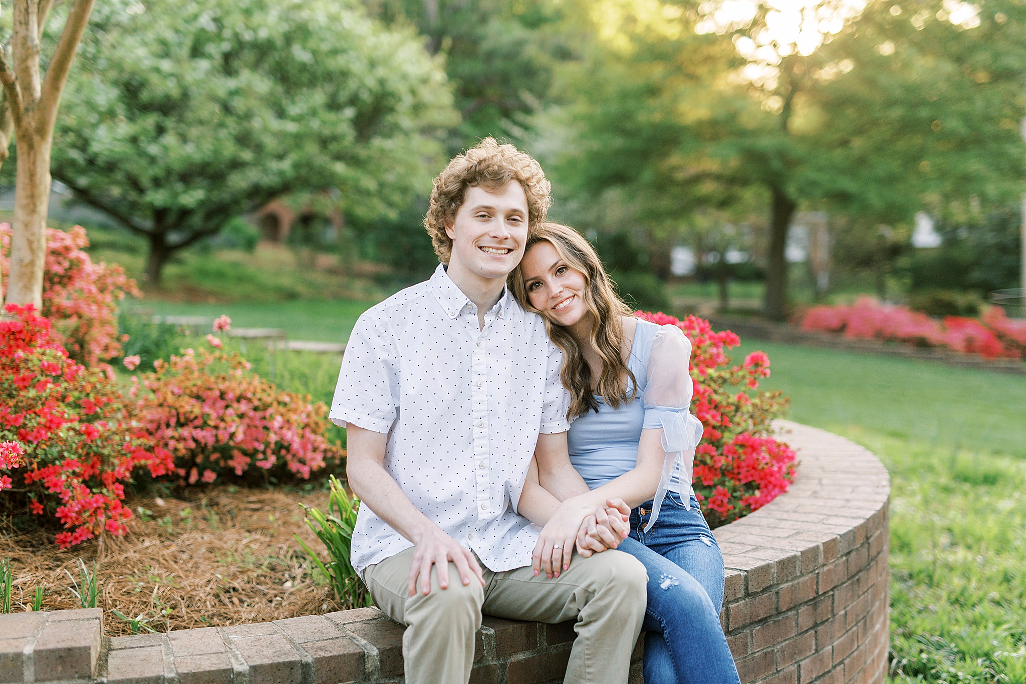 bride and groom sit on stone wall in Glencairn Gardens