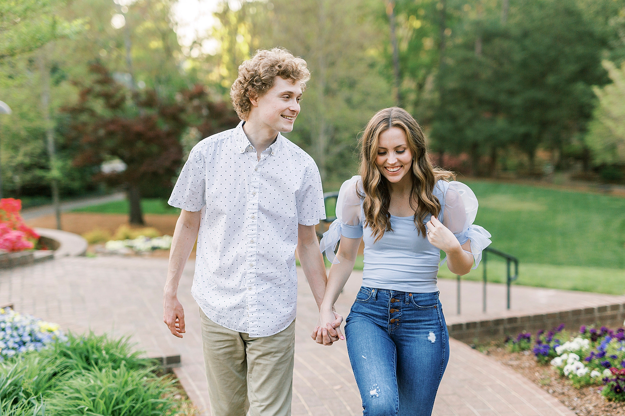 engaged couple walks through brick pathway at Glencairn Gardens