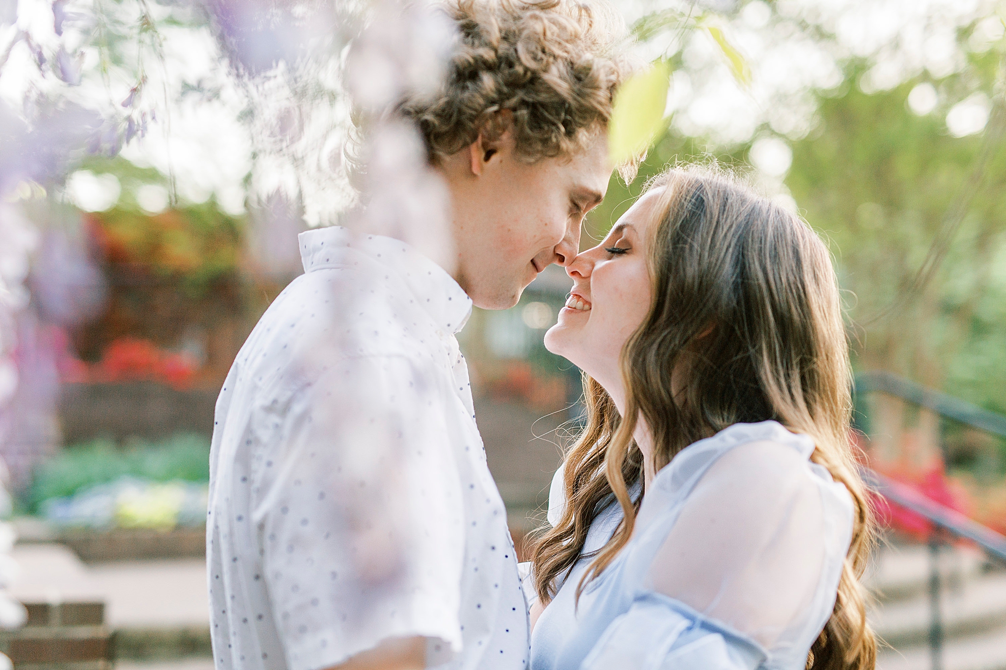 couple poses under tree with purple flowers in Rock Hill SC