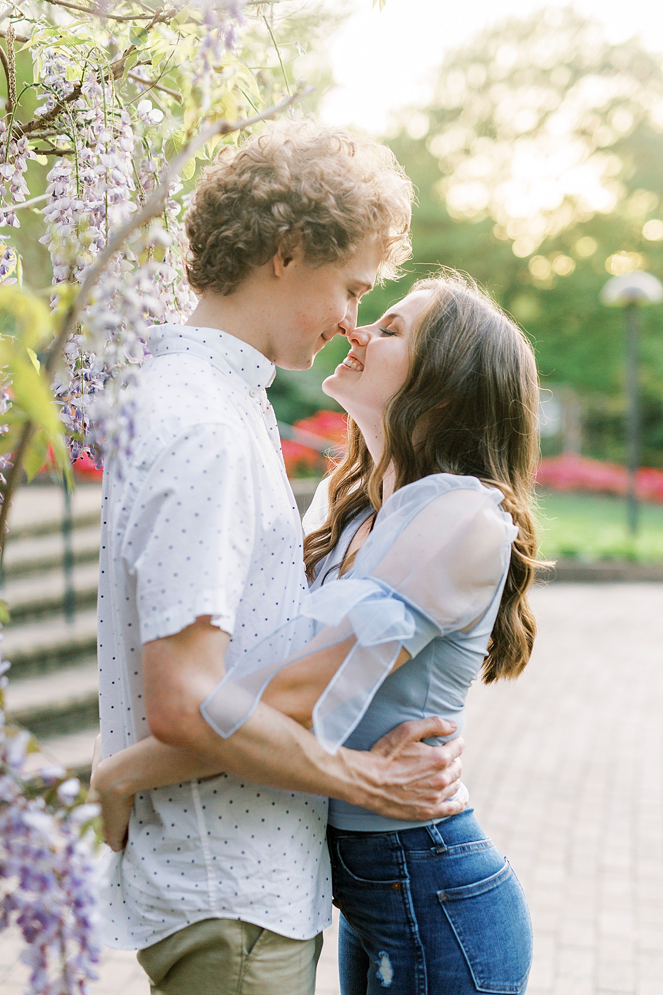 engaged couple walks through purple trees in Glencairn Gardens