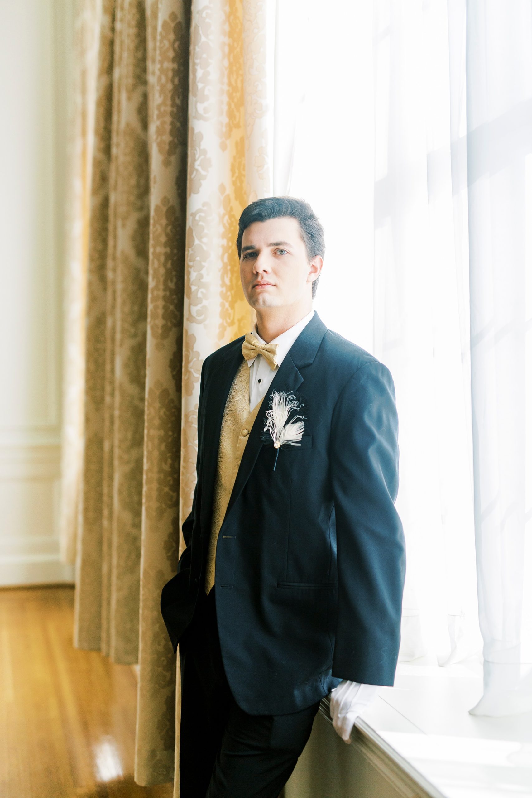 young man in suit poses by window at The Hotel Concord