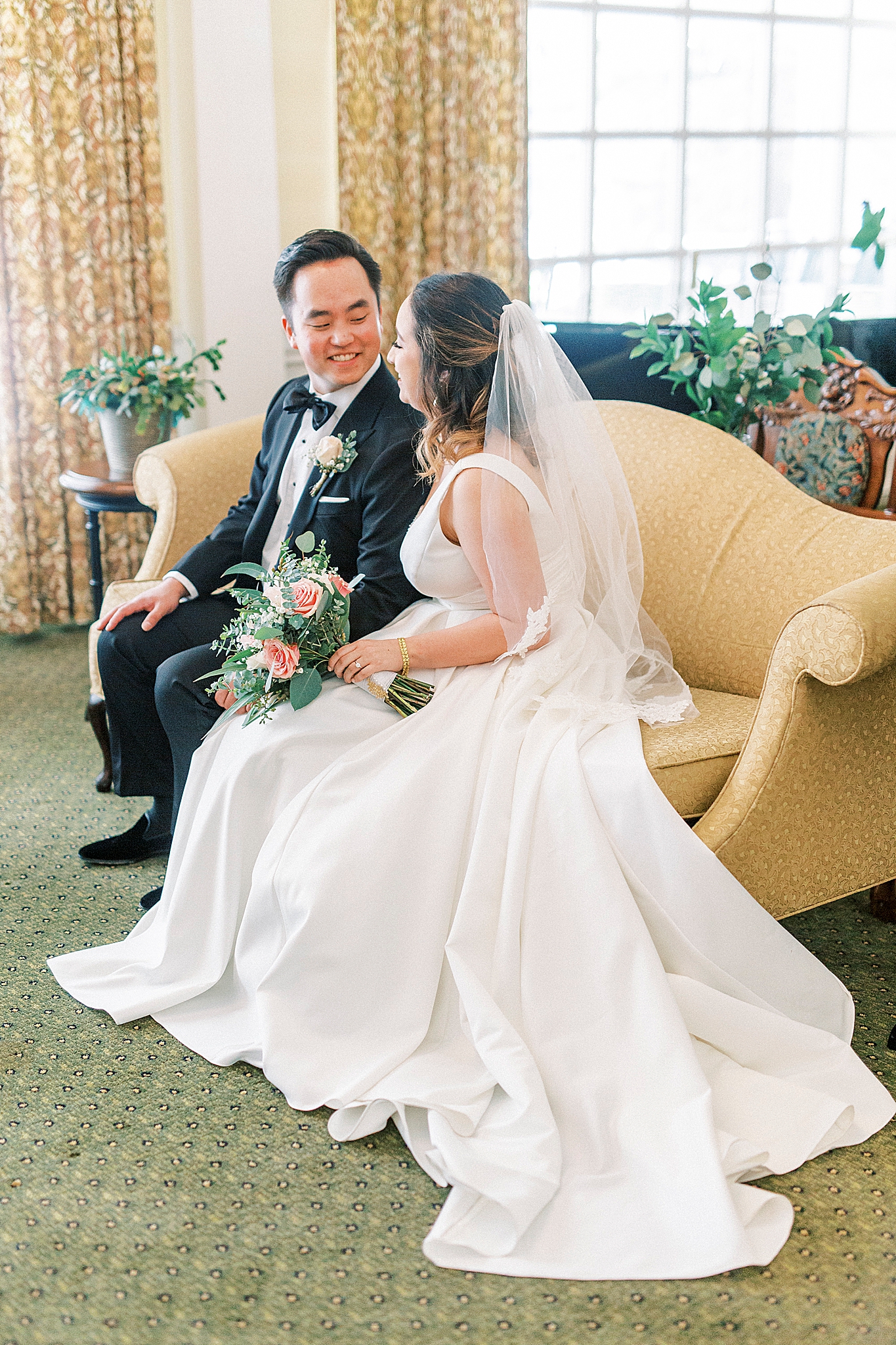 bride and groom sit on mustard colored couch