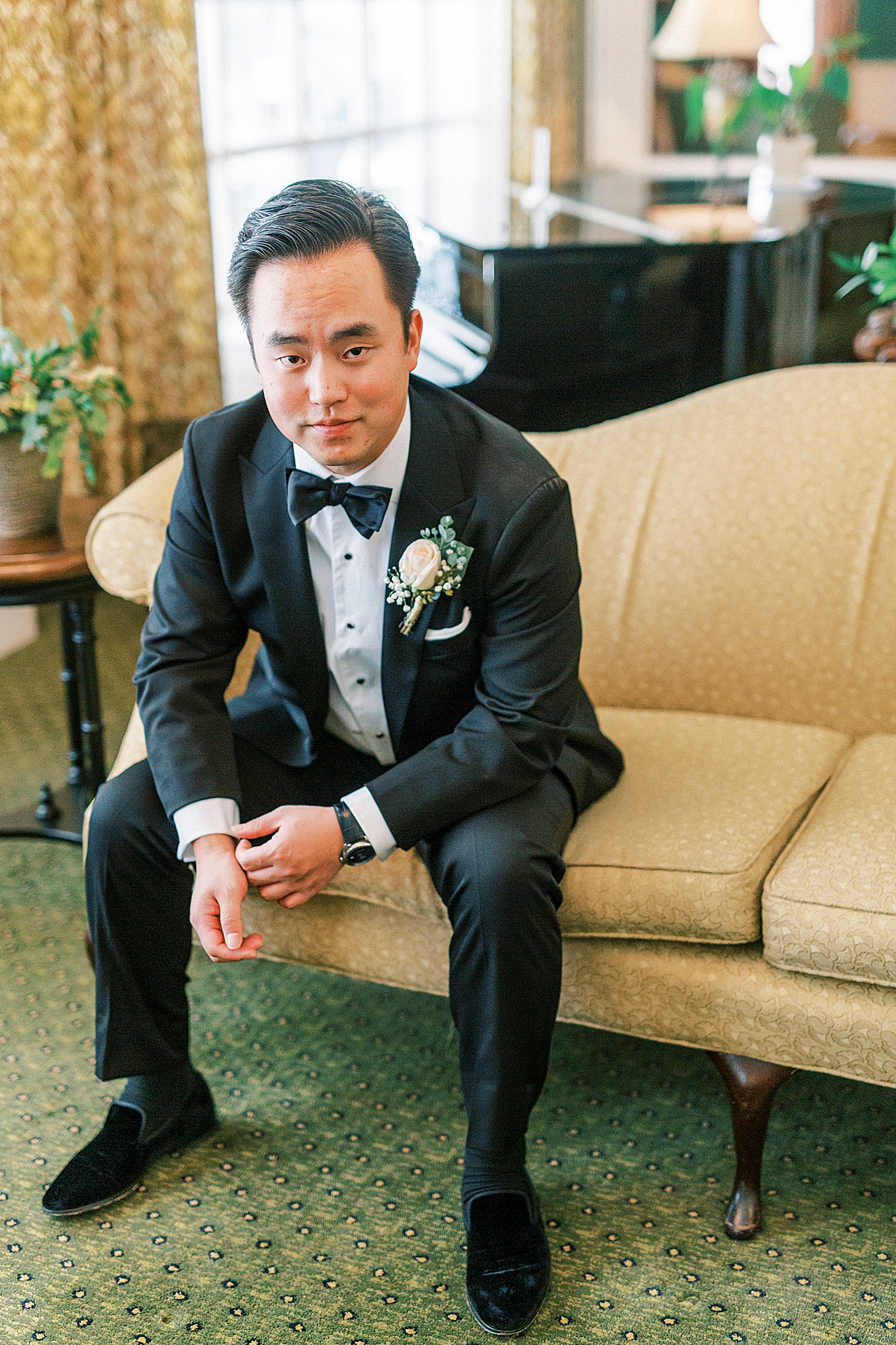 groom leans on legs wearing classic tux
