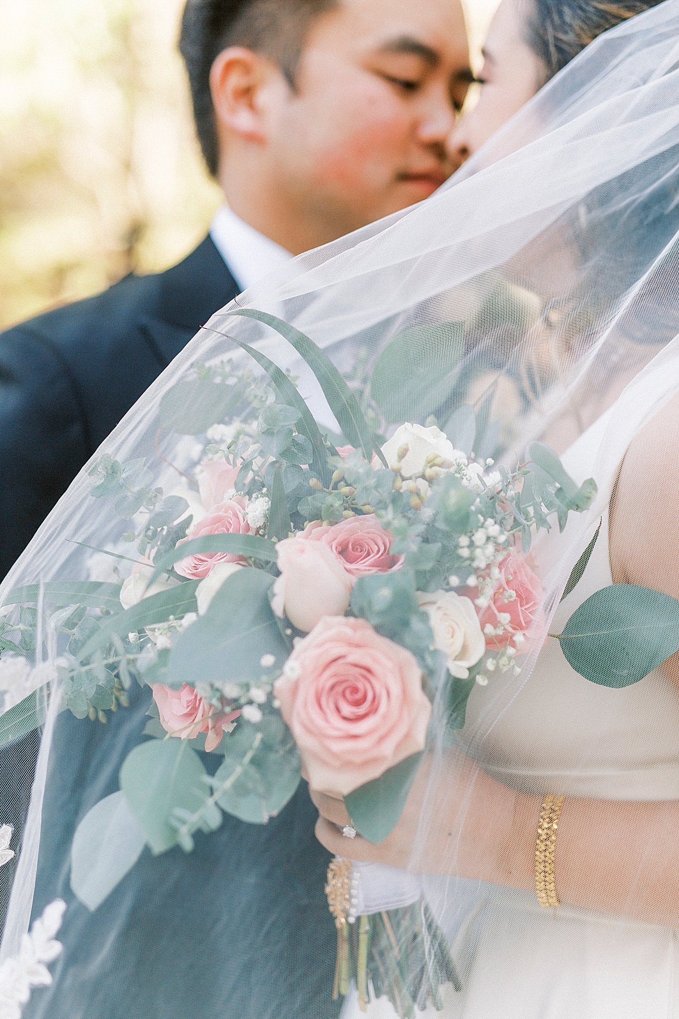 bride and groom lean in for kiss as veil floats by
