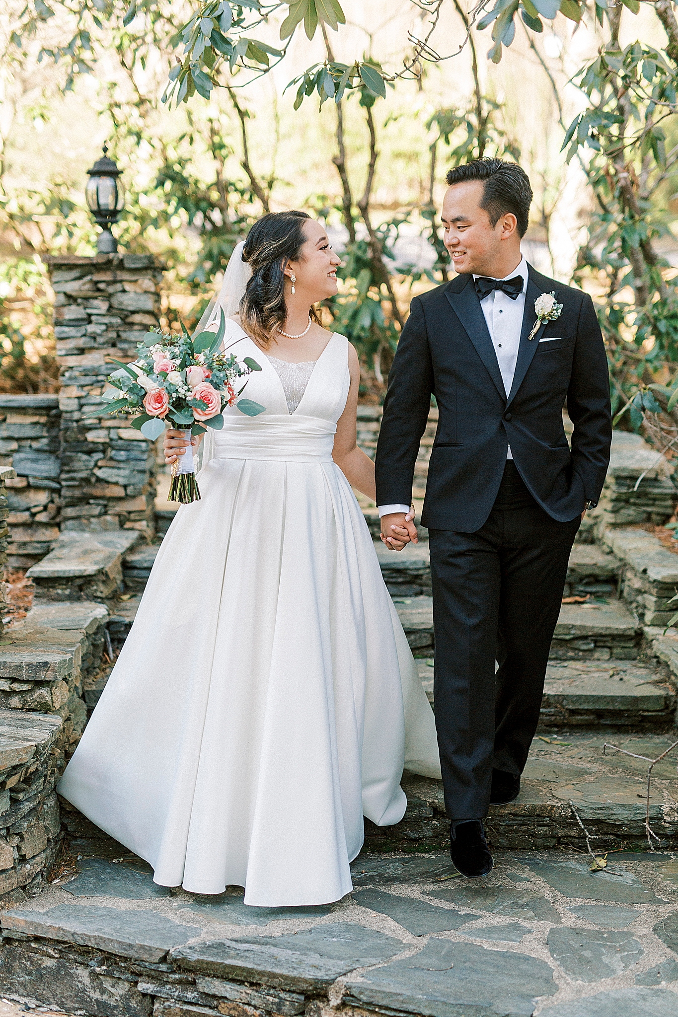 bride and groom hold hands walking down stone steps