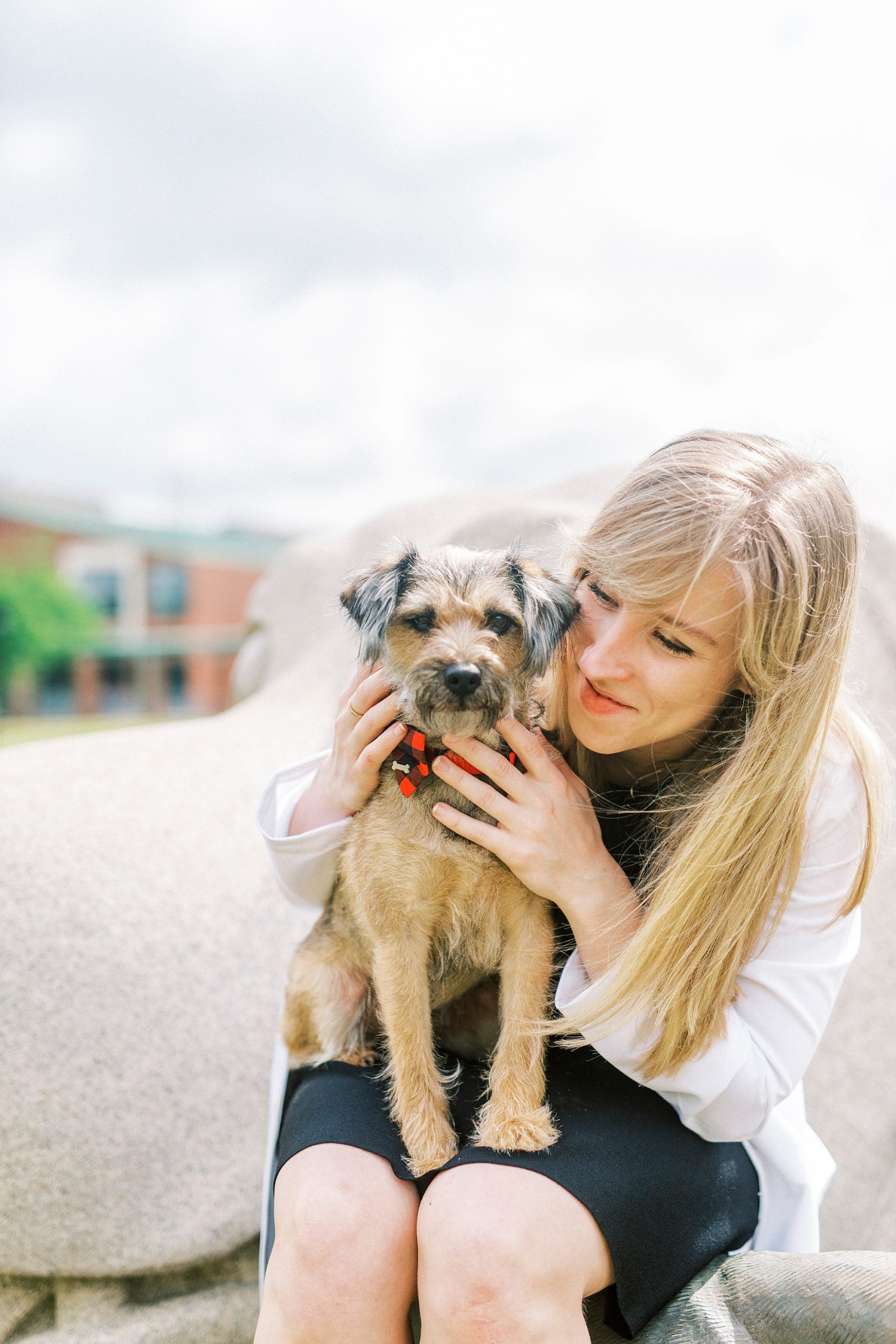 graduate in white doctor's coat snuggles with dog