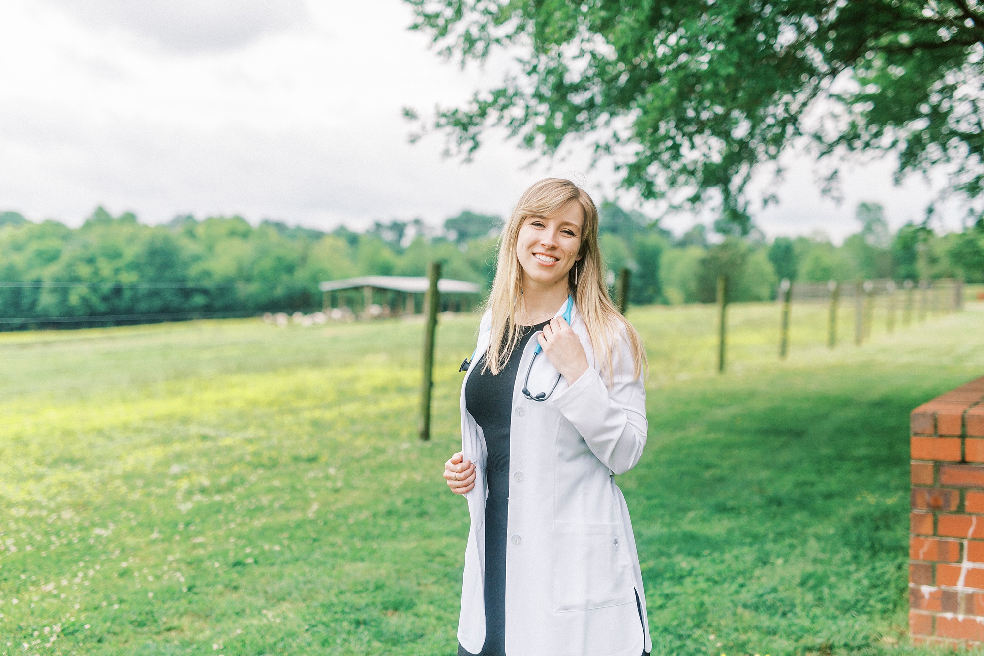 college graduate poses in white coat for NC State Vet School senior portraits