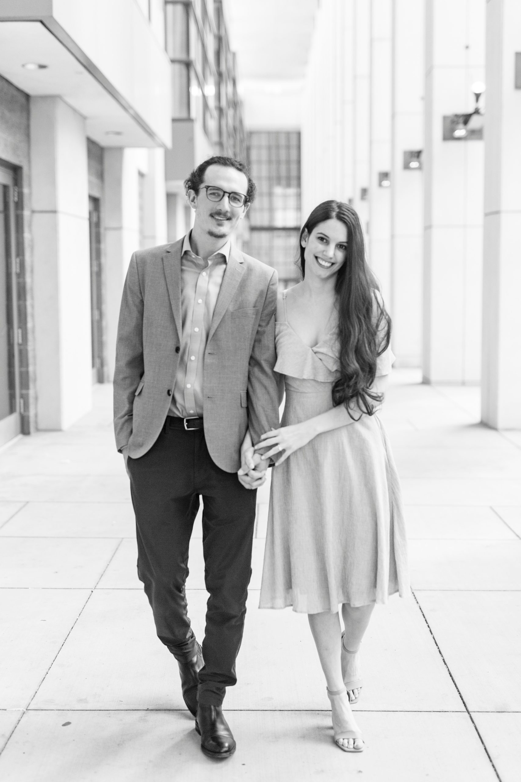 bride and groom hold hands walking through convention center