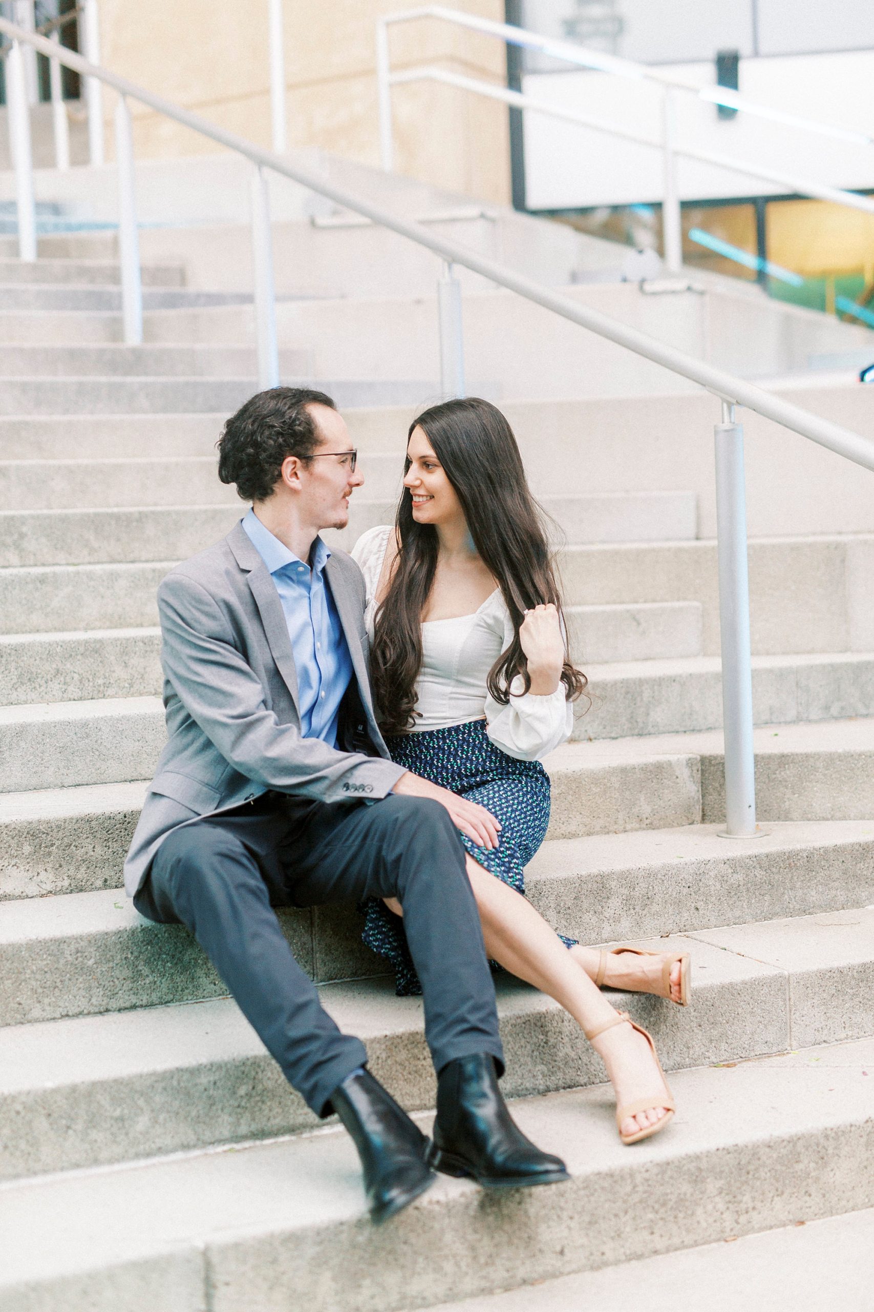 engaged couple sits on steps at The Mint Museum