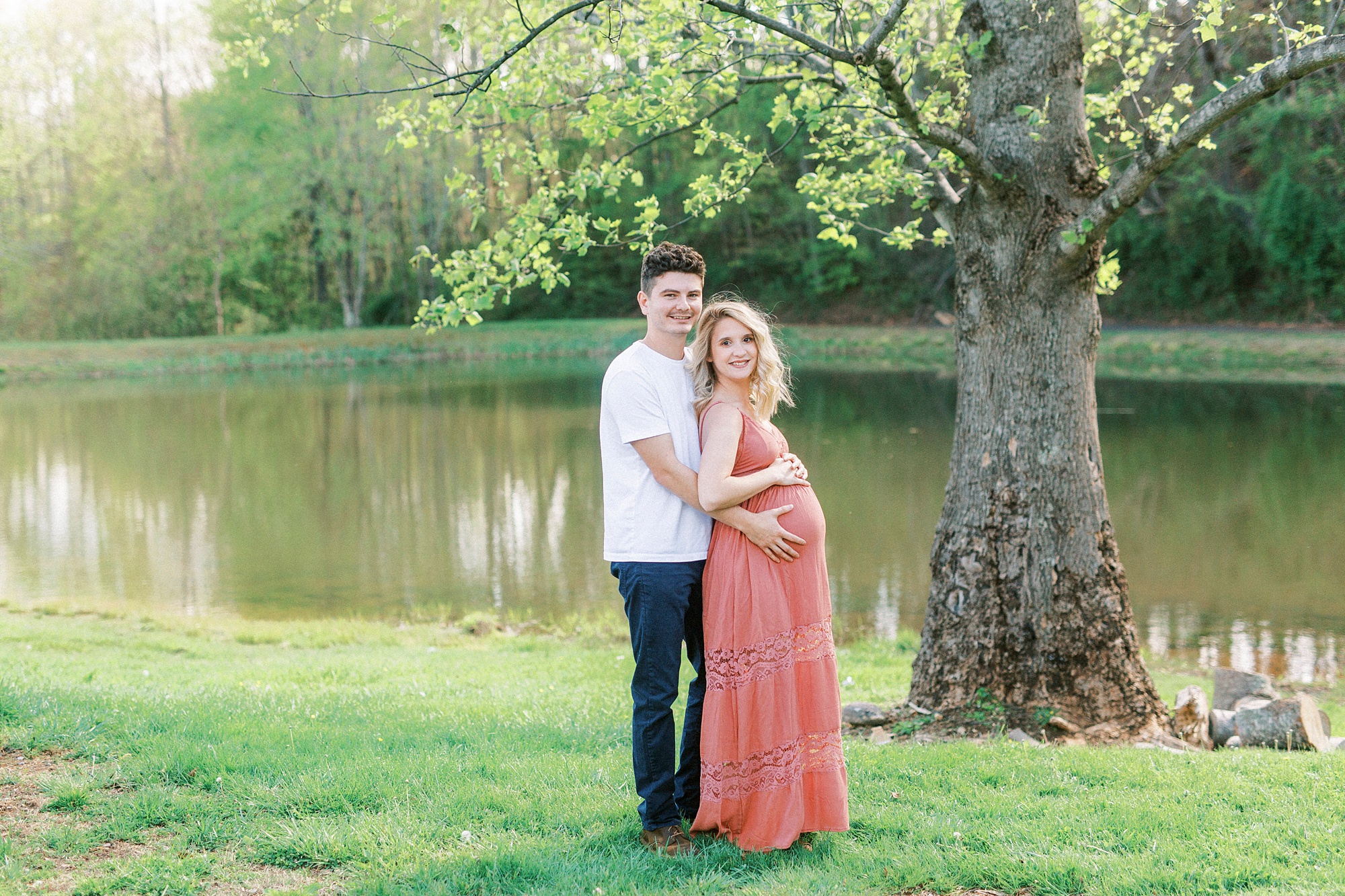 couple hugs by lake during Winston-Salem maternity photos