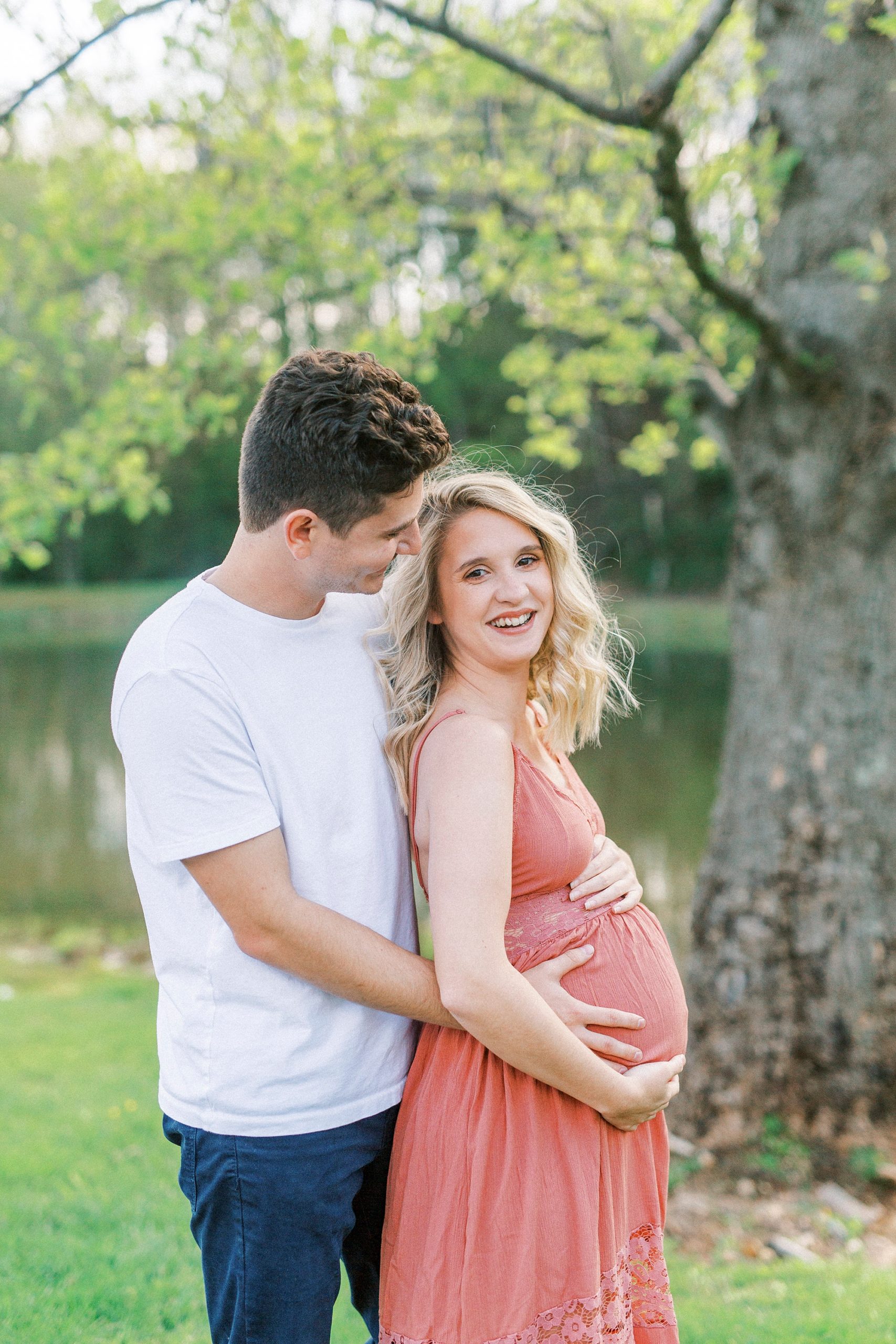 man hugs expecting woman from behind during maternity photos