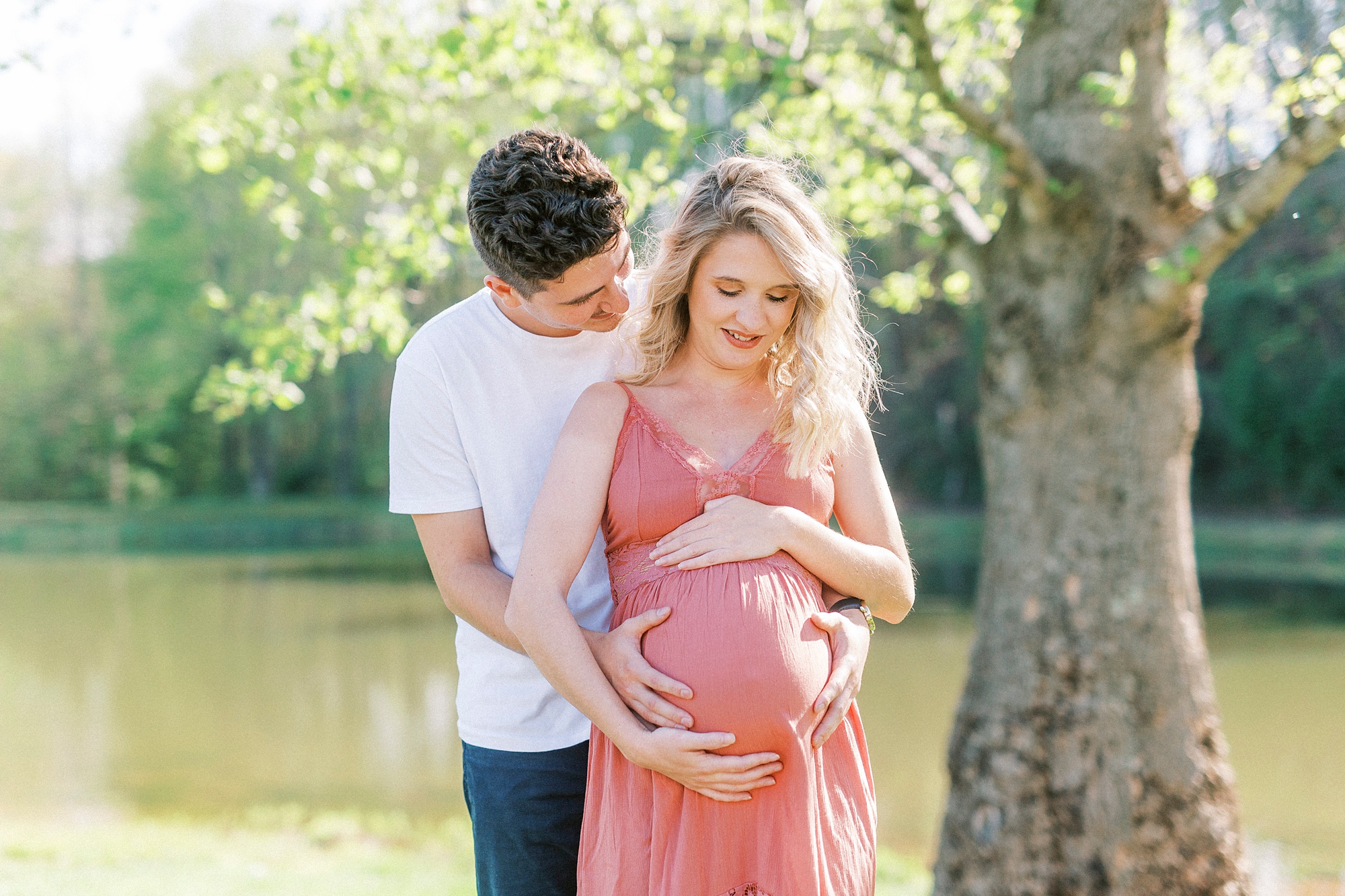 couple looks down at woman's belly during Winston-Salem maternity photos