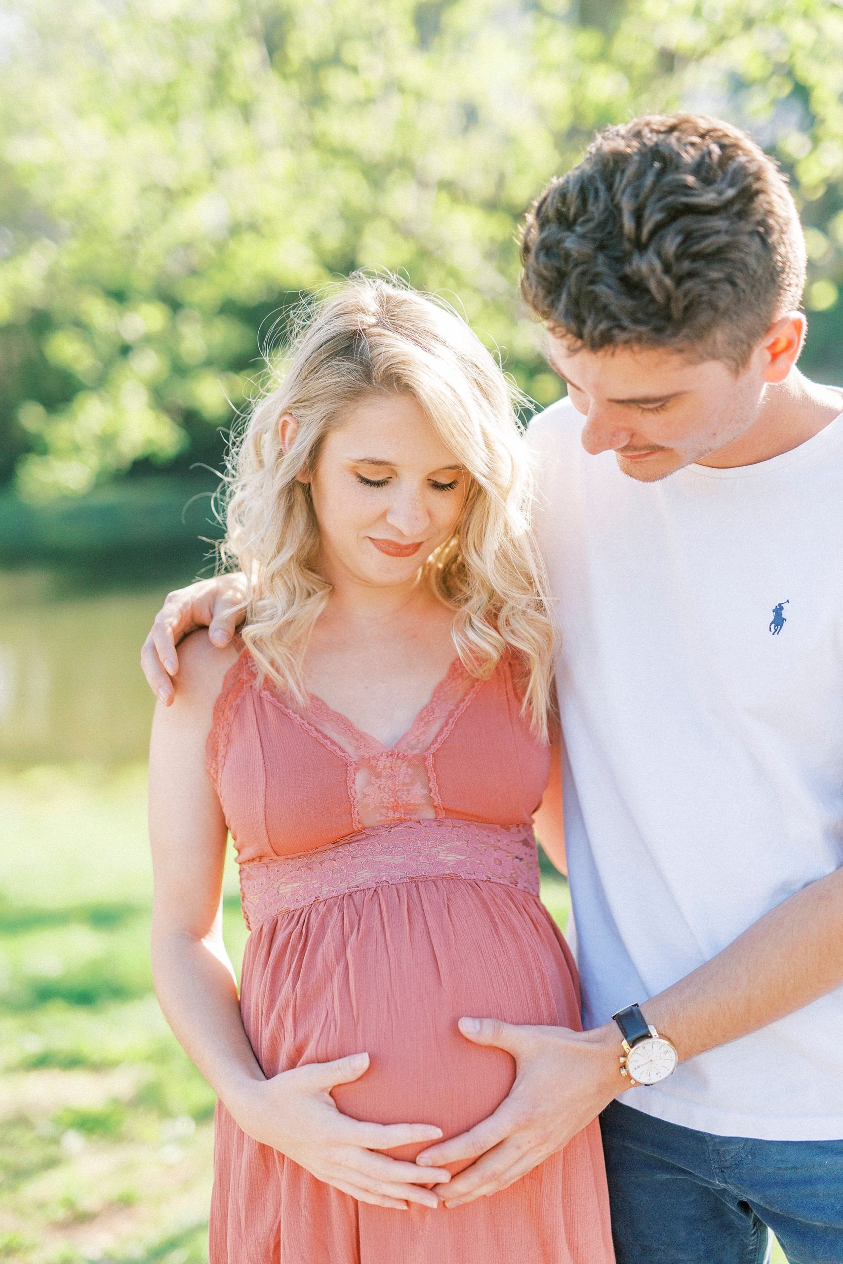 man looks down at woman's belly during Winston-Salem maternity photos