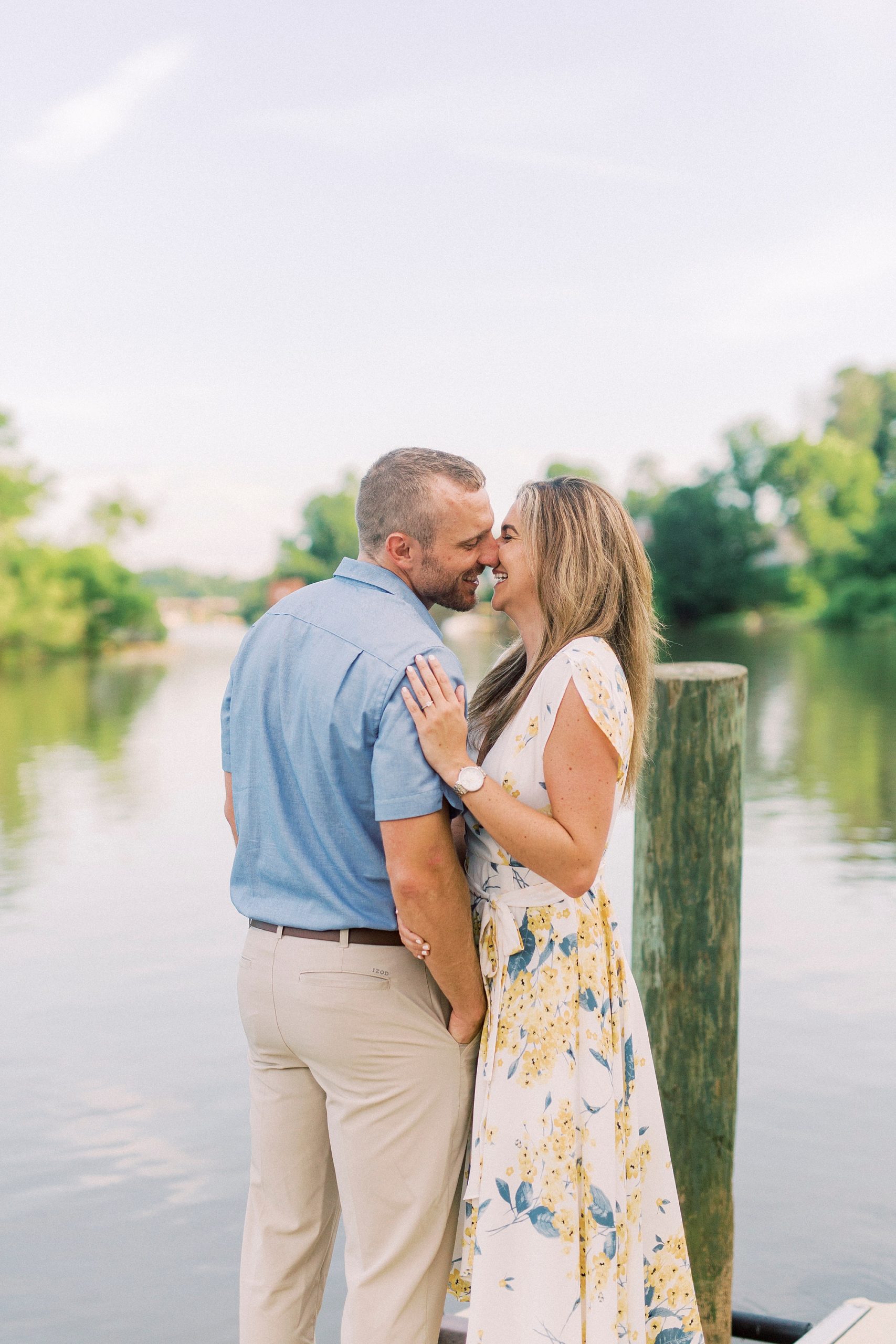 bride and groom nuzzle noses on pier