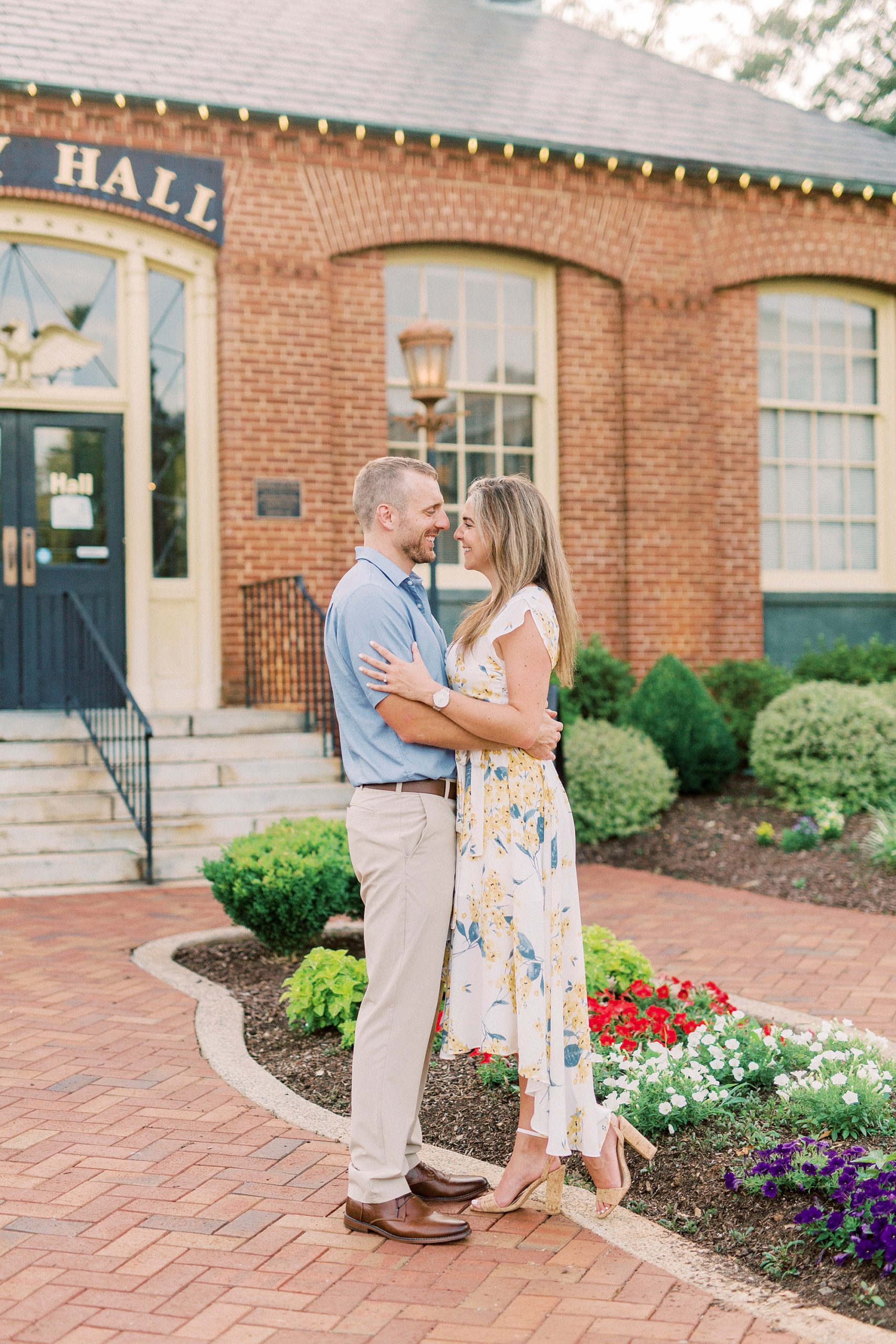 engaged couple hugs outside City Hall in Downtown Belmont