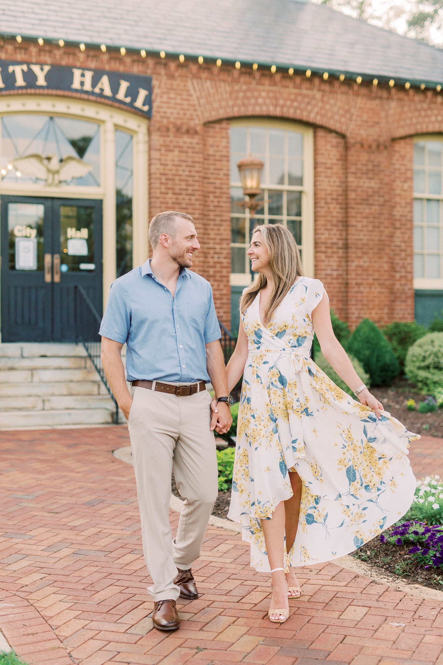 engaged couple walks by brick City Hall