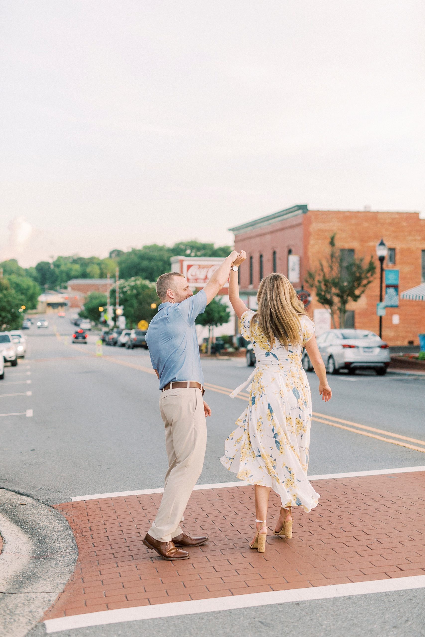 groom twirls bride in crosswalk during Downtown Belmont engagement session