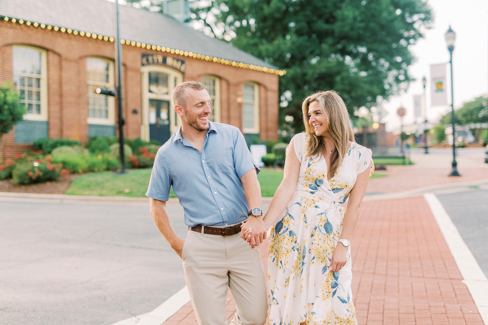 engaged couple bumps hips while walking down street