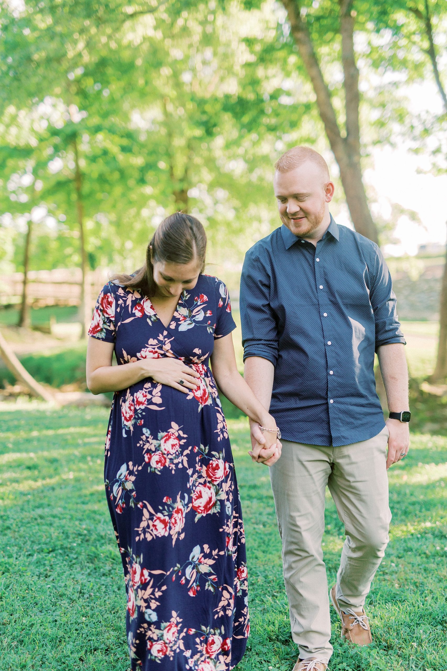 mother looks down at belly walking with dad during maternity photos in Rankin Lake Park