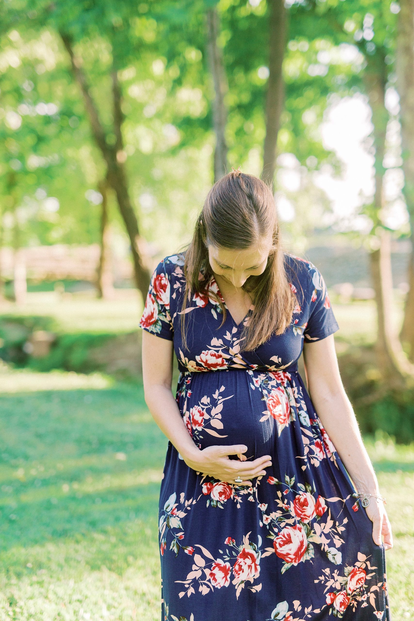 mom holds baby belly and looks down during Rankin Lake Park maternity session