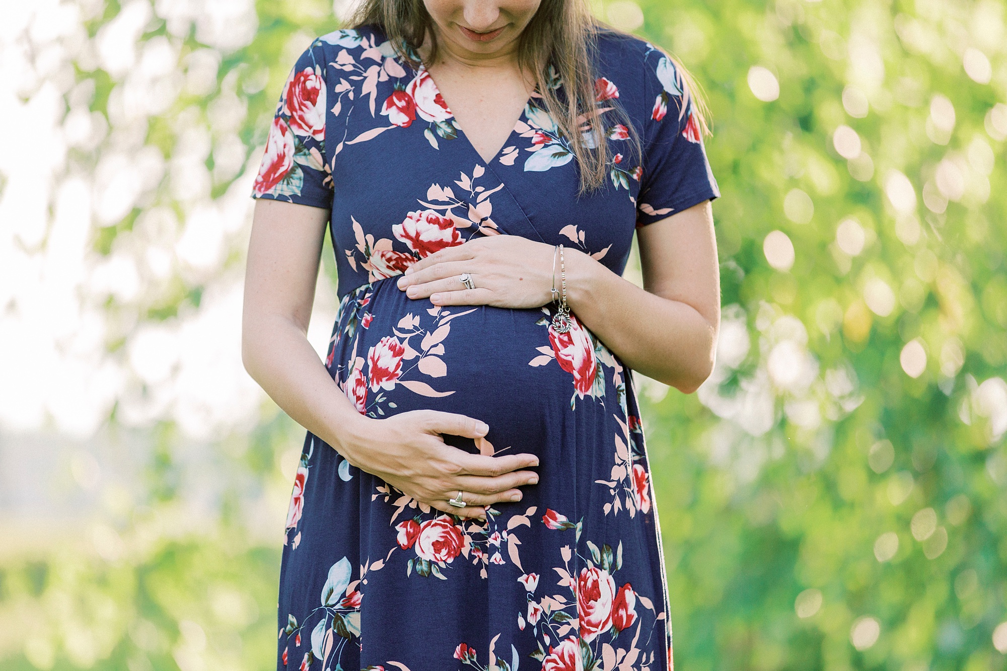 mom holds belly during maternity session in Gastonia NC park